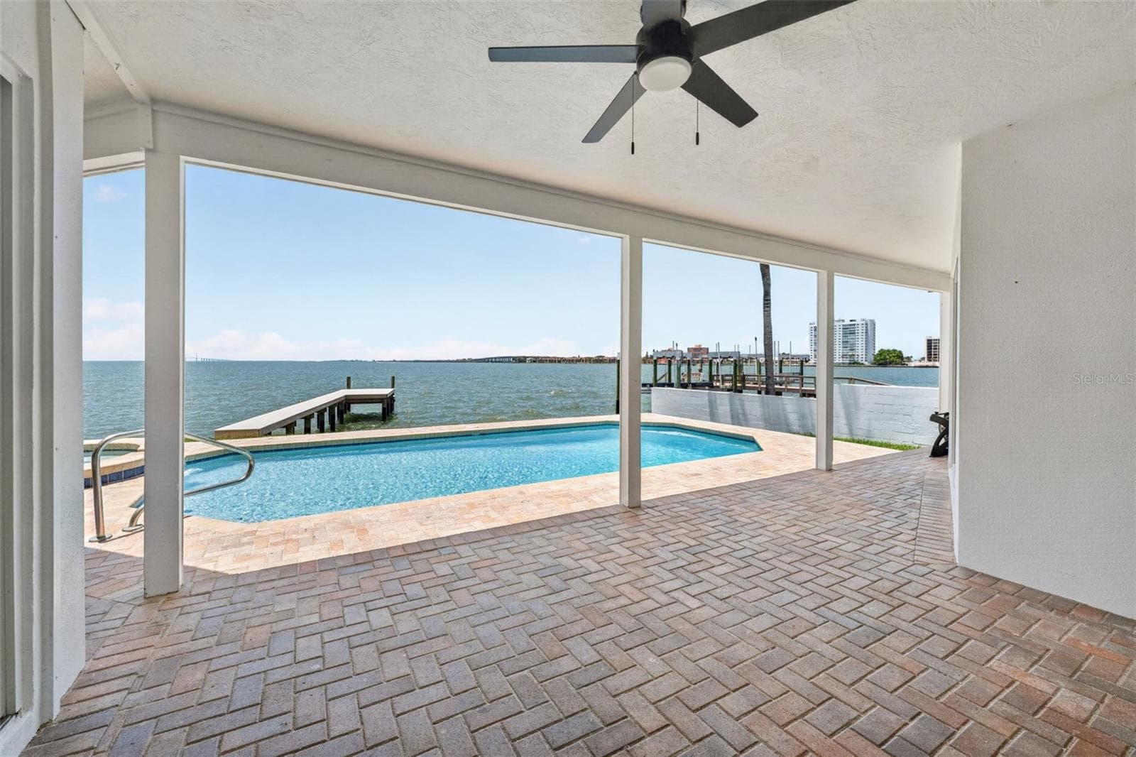 Covered back patio with stunning views of the pool and Tampa Bay, perfect for enjoying the outdoors in comfort. - 2936 68TH AVE S, ST PETERSBURG