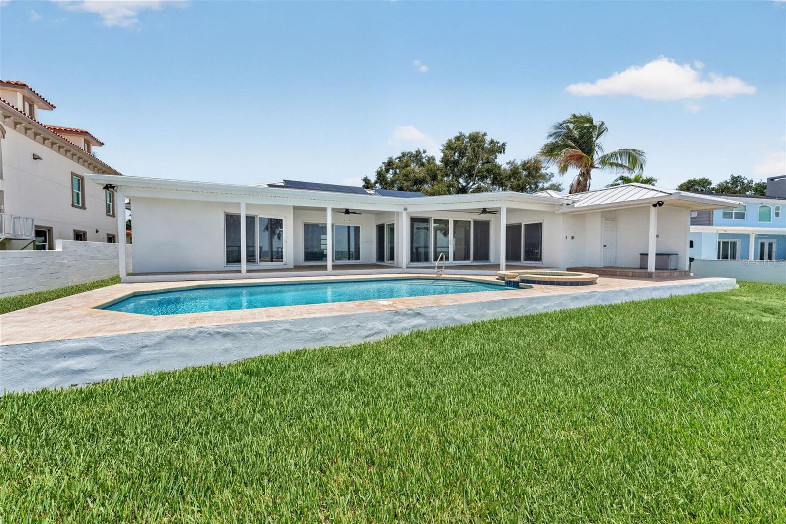 Beautiful outdoor space viewed from the seawall, showcasing the pool, patio, and backyard leading up to the home. - 2936 68TH AVE S, ST PETERSBURG