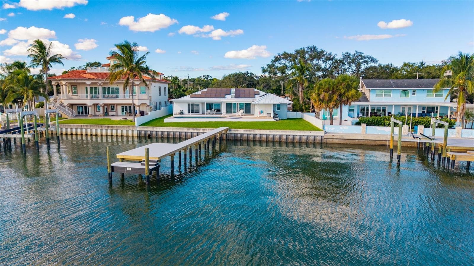 Drone view from the water highlighting the backyard, pool, home, and newly installed dock, all set against stunning waterfront scenery. - 2936 68TH AVE S, ST PETERSBURG