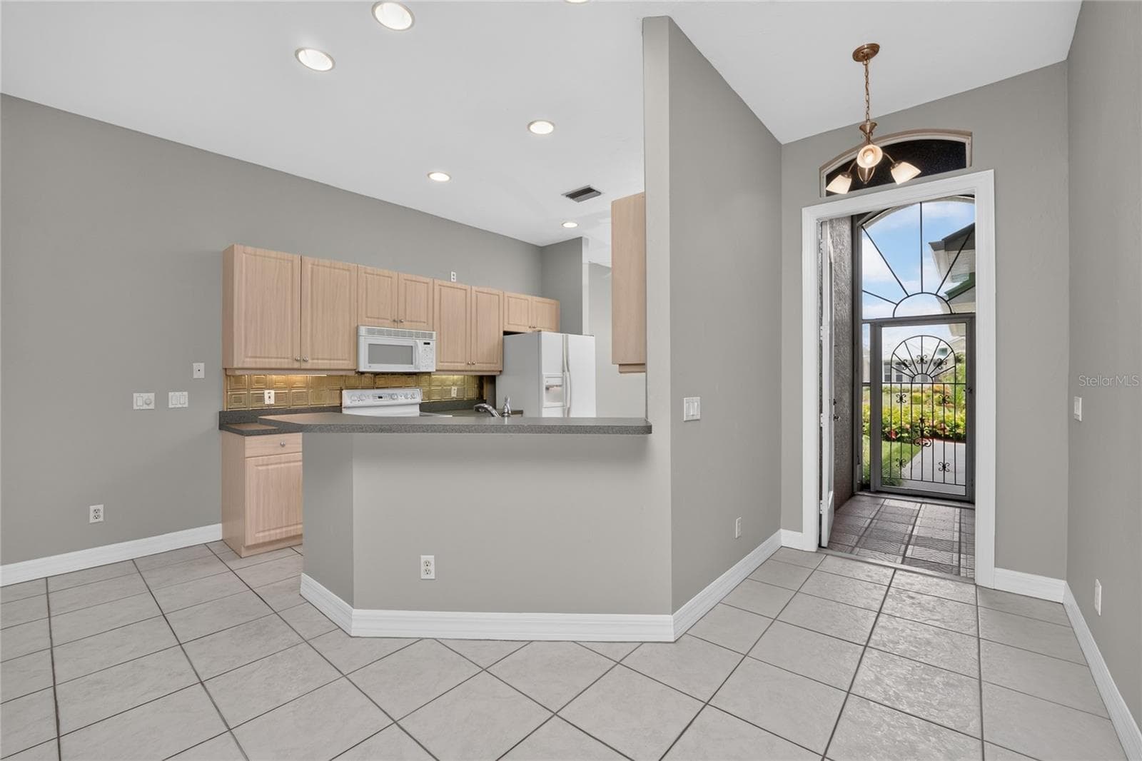 View of the kitchen, foyer and tiled front entry from the great room. - 1611 ATARES DRIVE #Unit 111, PUNTA GORDA