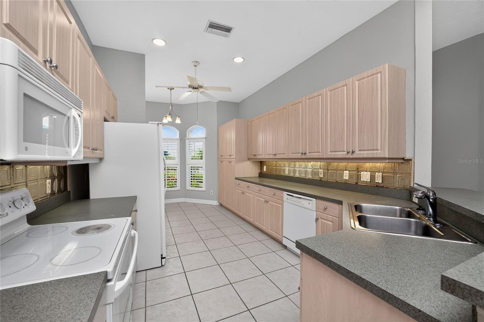Kitchen with under cabinet lighting and faux patina tile backsplash. - 1611 ATARES DRIVE #Unit 111, PUNTA GORDA