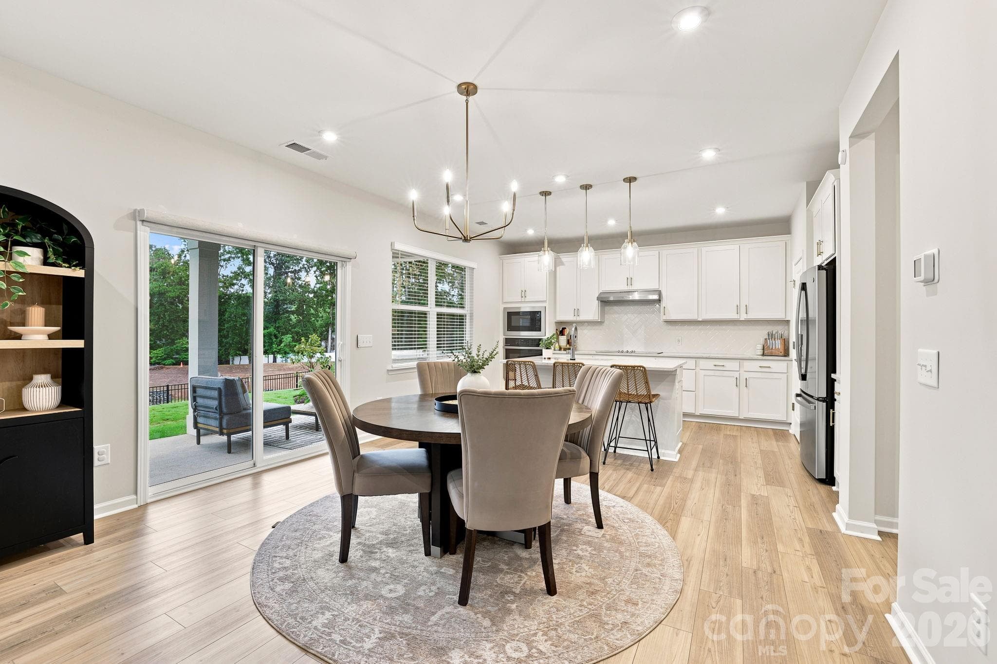 Dining table conveniently located between the Kitchen and Family Room- all with LVP flooring and lots of natural light streaming in.  Eaasy access to covered oversized patio! - 8226 Franklin Trail Street, Mint Hill
