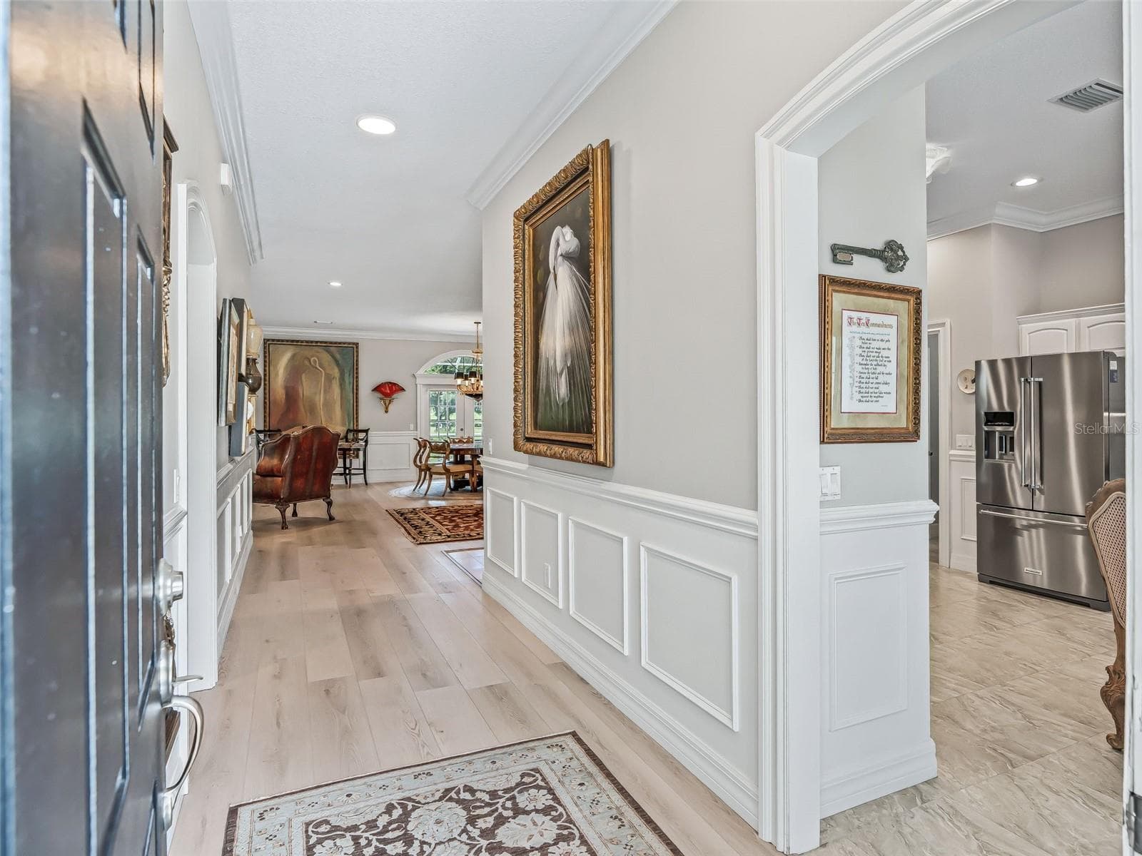 Step inside to a bright and welcoming foyer featuring decorative wall molding, neutral finishes, tile flooring, and an open sightline into the home's spacious living areas. - 714 CIMARRON AVE, THE VILLAGES