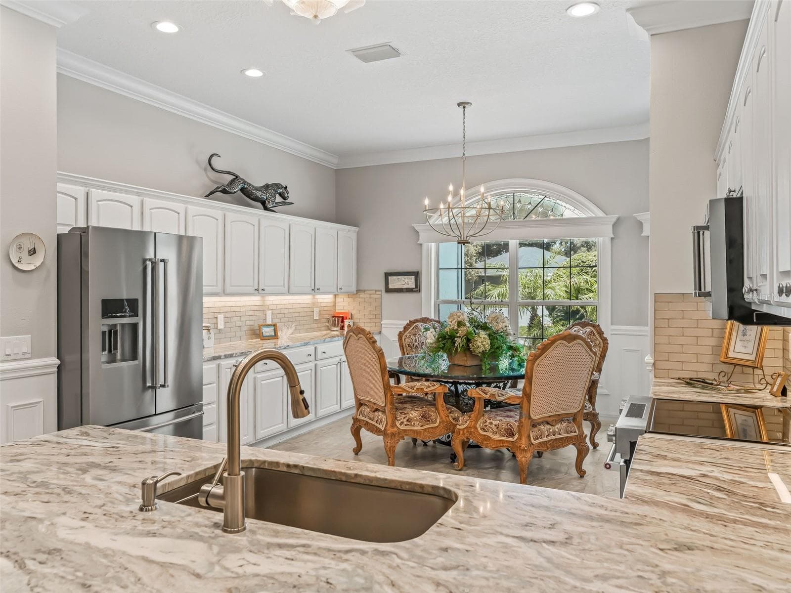 Spacious kitchen features stylish white crowned cabinetry, granite countertops, upgraded stainless steel appliances, tile backsplash, and generous prep and entertaining space. - 714 CIMARRON AVE, THE VILLAGES