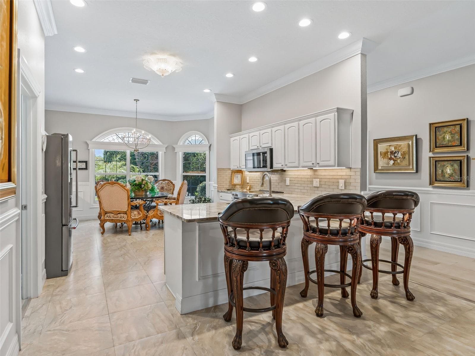 An inviting breakfast bar provides casual seating while white crowned cabinetry, granite surfaces, and recessed lighting create a bright and polished kitchen. - 714 CIMARRON AVE, THE VILLAGES
