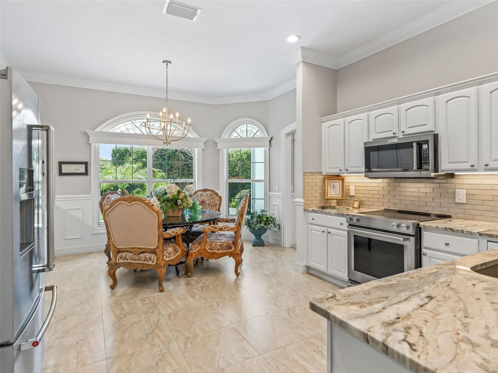 The 24'x14.6' kitchen has a large dinette area where oversized windows and French doors fill the space with natural light and frame the beautiful outdoor surroundings. - 714 CIMARRON AVE, THE VILLAGES