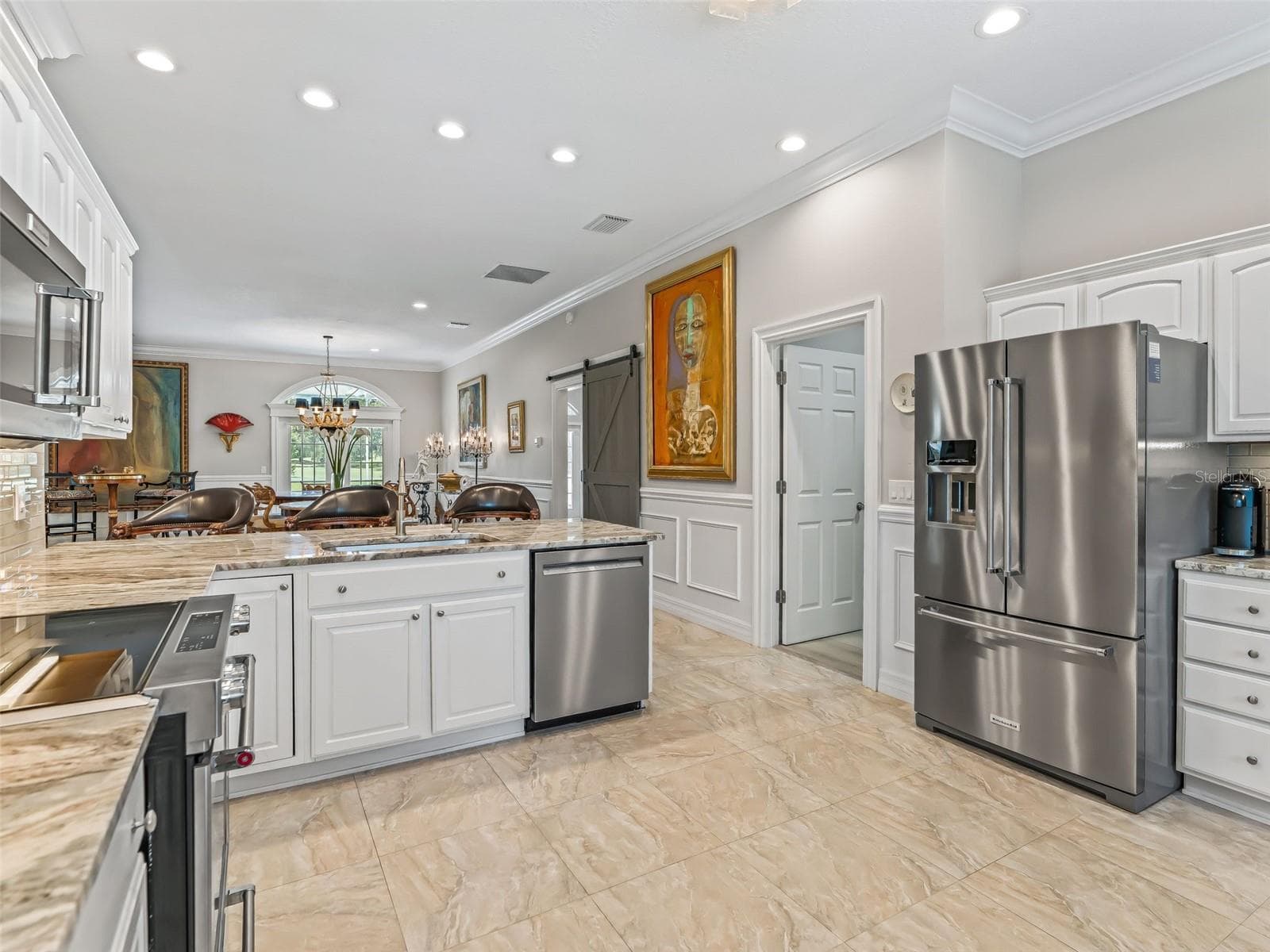 Wide-angle view showcases the kitchen's impressive amount of cabinetry and counter space, upgraded appliances, marble tile flooring, and easy connection to the home's main dining & living areas. - 714 CIMARRON AVE, THE VILLAGES