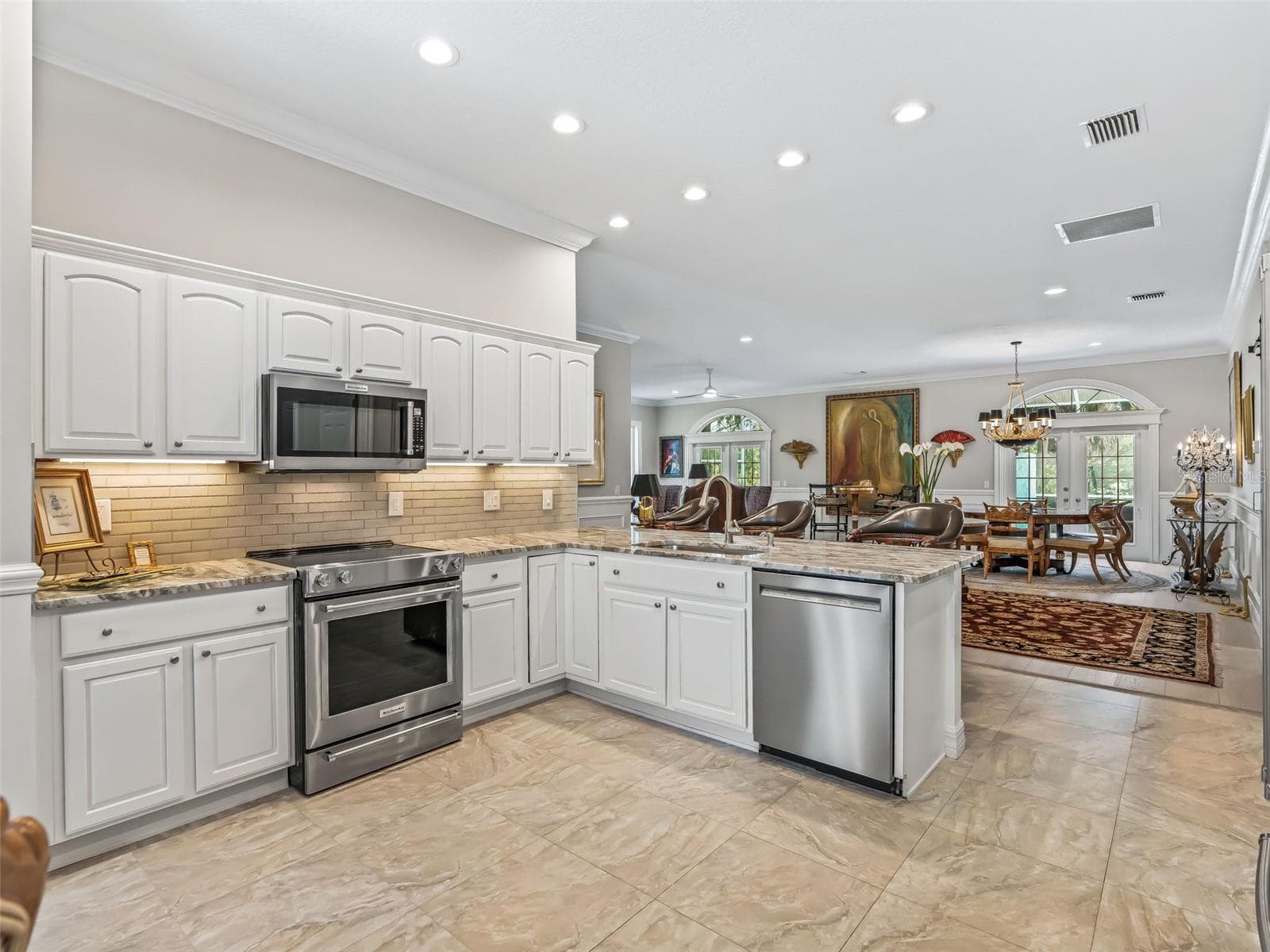 Designed for entertaining, the kitchen features granite countertops, extensive white cabinetry, stainless steel appliances, recessed lighting, and a large peninsula overlooking the dining & living area. - 714 CIMARRON AVE, THE VILLAGES