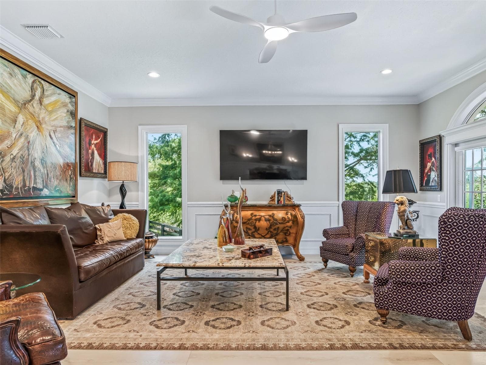 The main living area is framed by tall windows and French doors, creating a bright interior while providing easy access to the screened lanai, pool, and spectacular golf course setting. - 714 CIMARRON AVE, THE VILLAGES