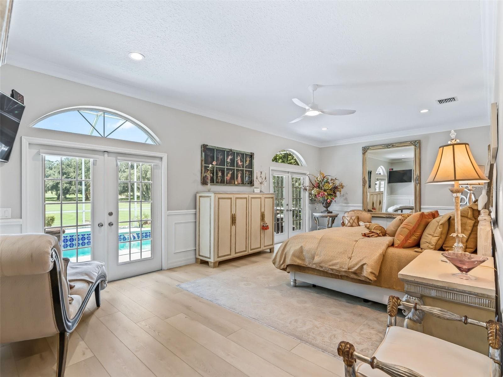 The spacious 28'x14' primary bedroom is designed as a relaxing retreat, featuring abundant natural light, elegant finishes, and private French doors leading directly to the pool and lanai. - 714 CIMARRON AVE, THE VILLAGES