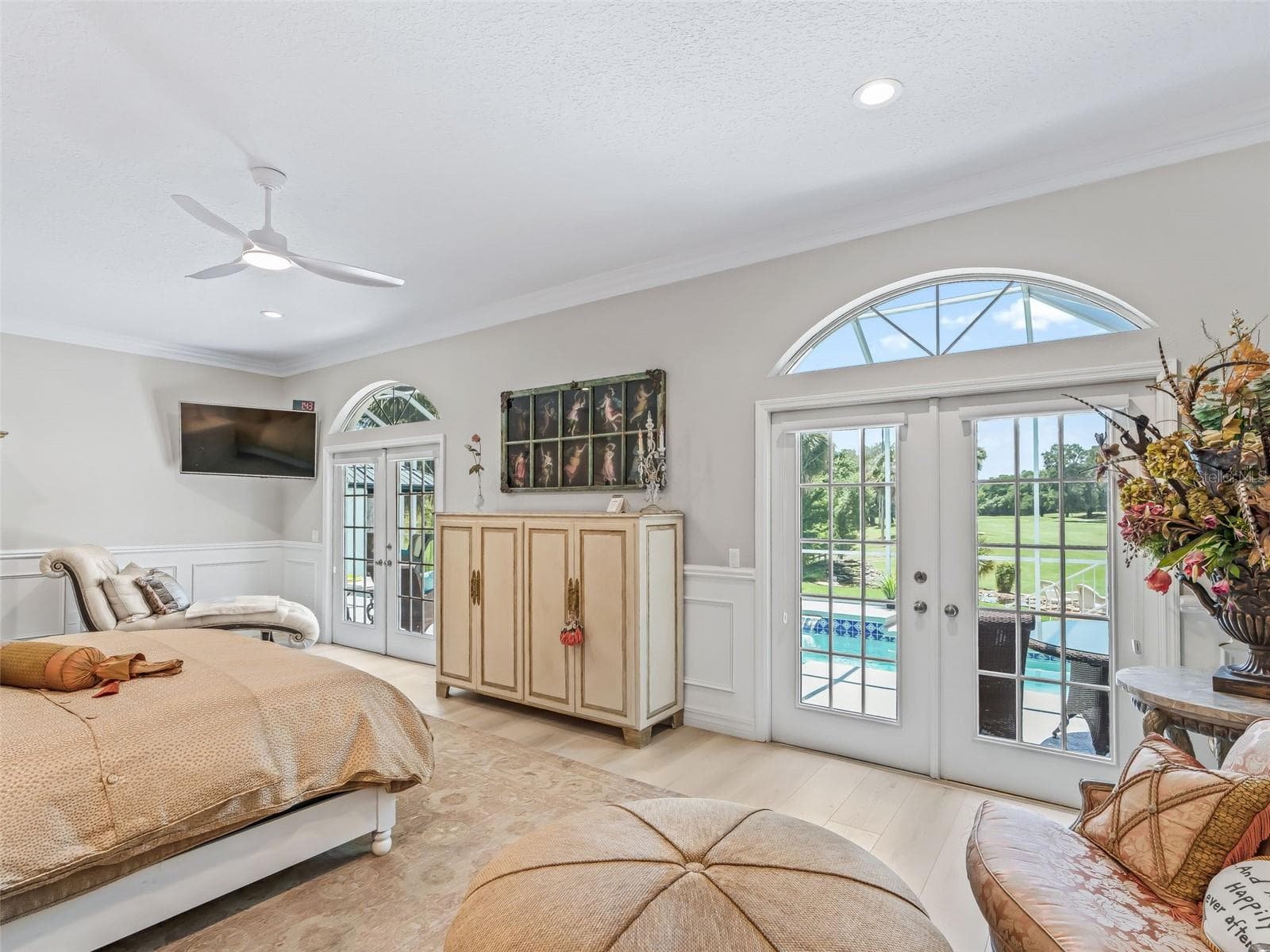 The primary bedroom enjoys beautiful natural light from French doors topped by an arched transom window, with direct access to the home's private outdoor oasis. - 714 CIMARRON AVE, THE VILLAGES