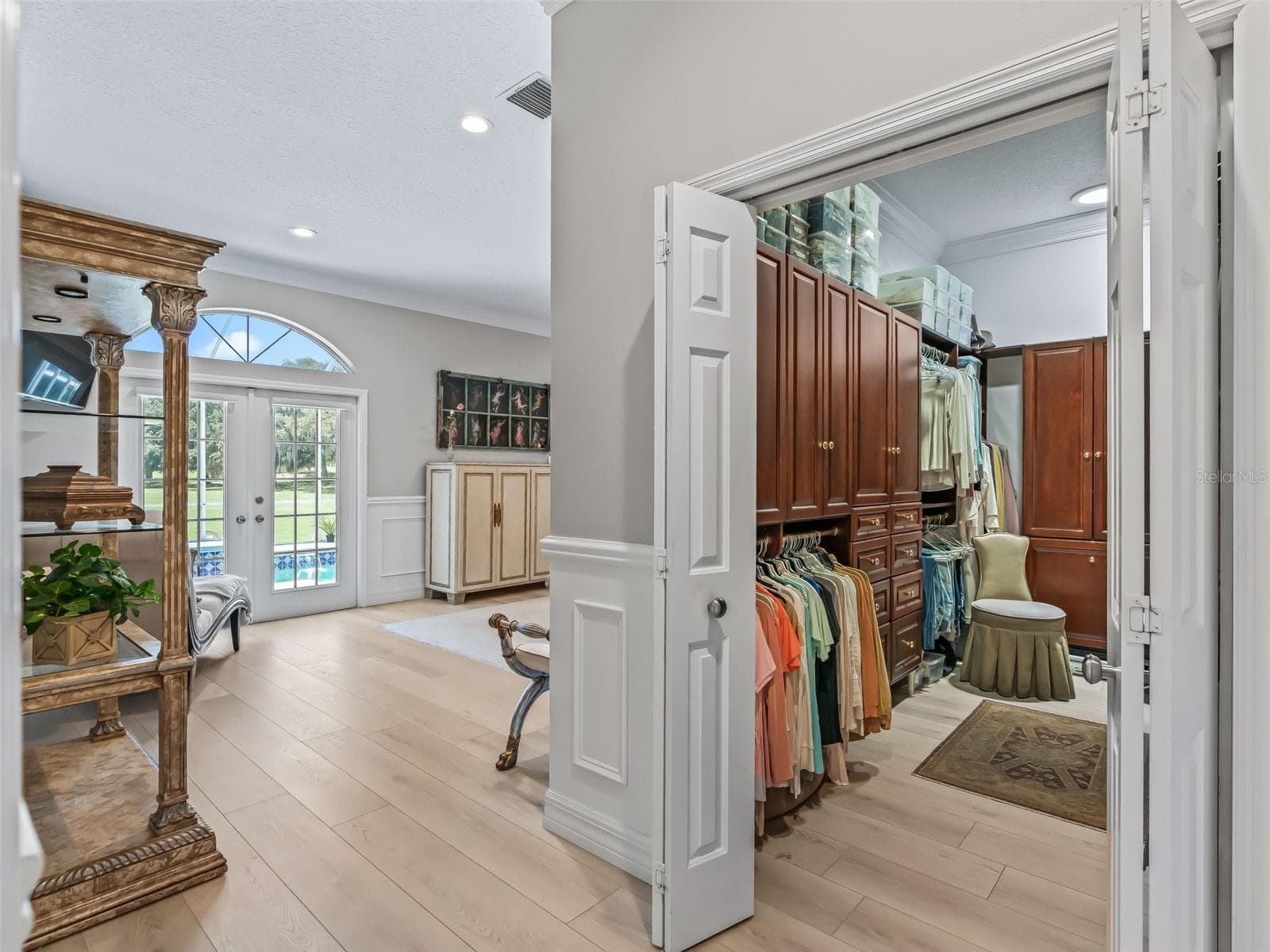 The primary suite opens to an impressive walk-in closet featuring extensive custom cherry wood built-ins, hanging space, shelving, and cabinetry for exceptional organization. - 714 CIMARRON AVE, THE VILLAGES