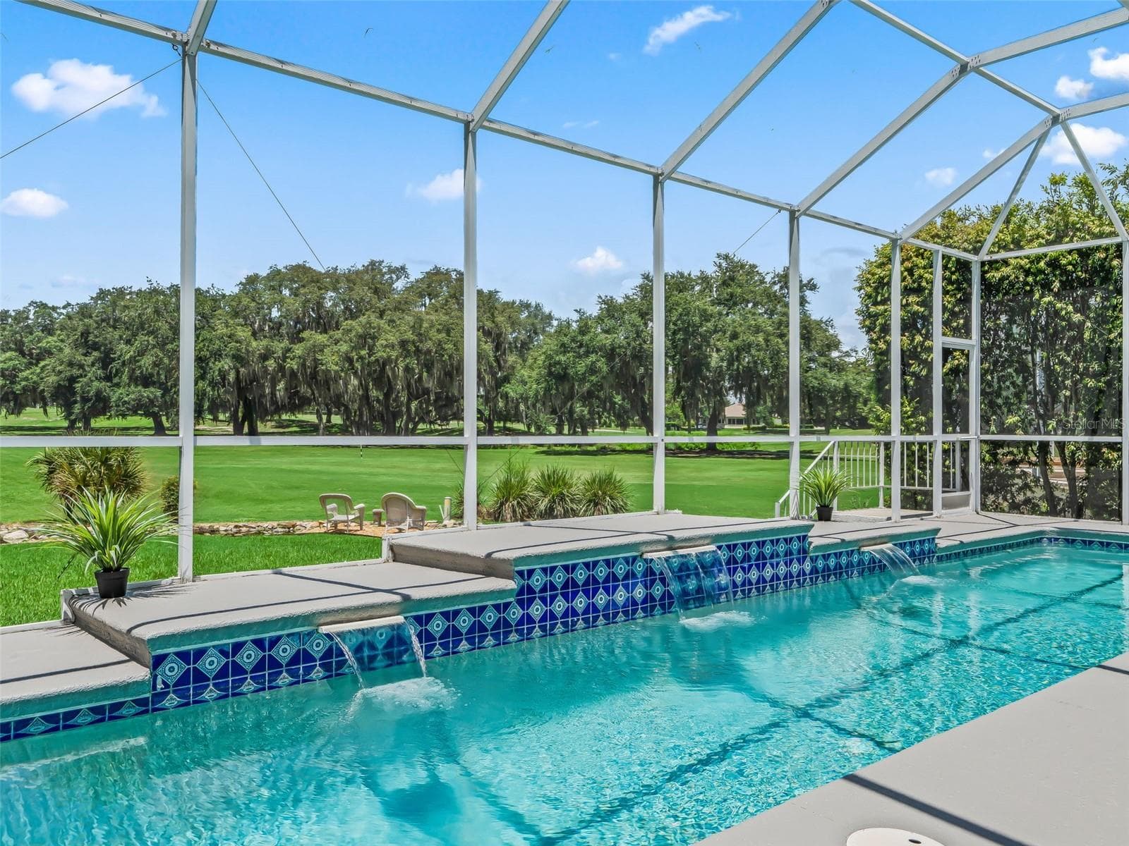 Relax beside the sparkling lap pool while enjoying long golf course views, lush landscaping, and the peaceful backdrop of the surrounding preserve. - 714 CIMARRON AVE, THE VILLAGES