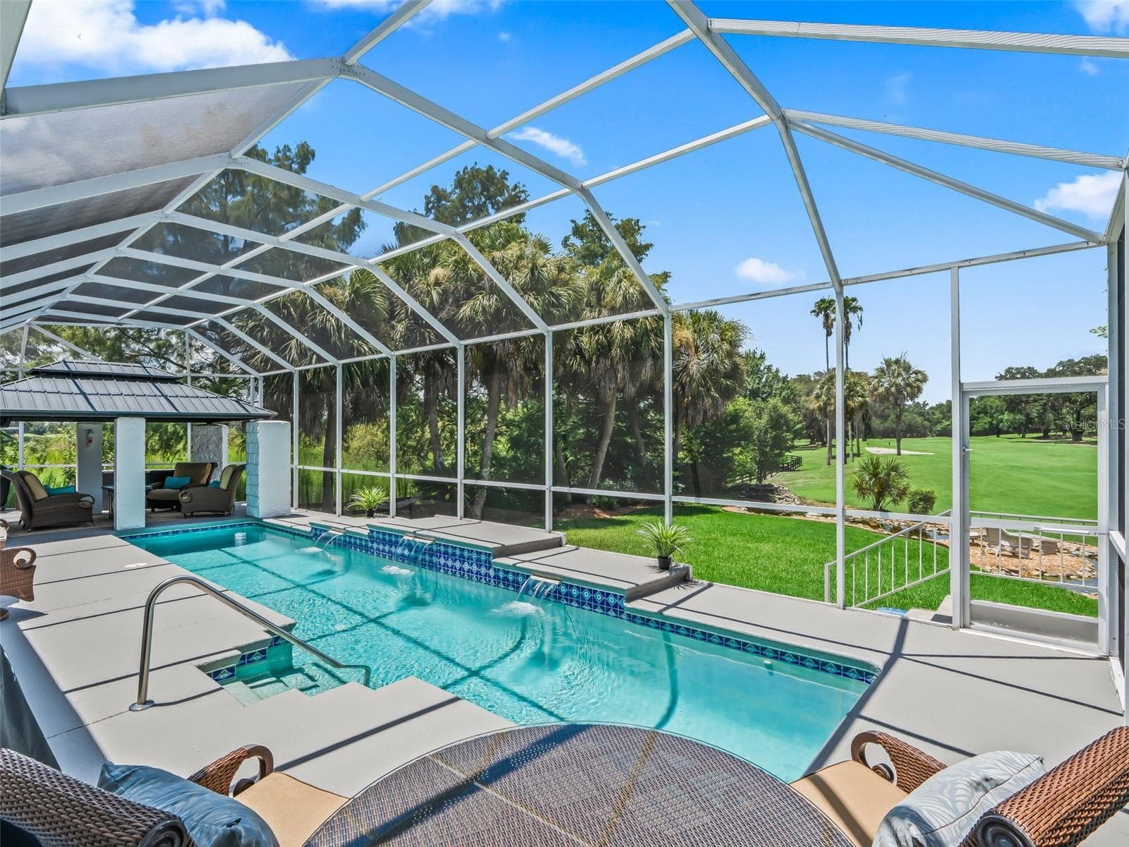 Another beautiful perspective of the pool area highlights the open golf course views, mature landscaping, and exceptional privacy of this Premier home's outdoor setting. - 714 CIMARRON AVE, THE VILLAGES