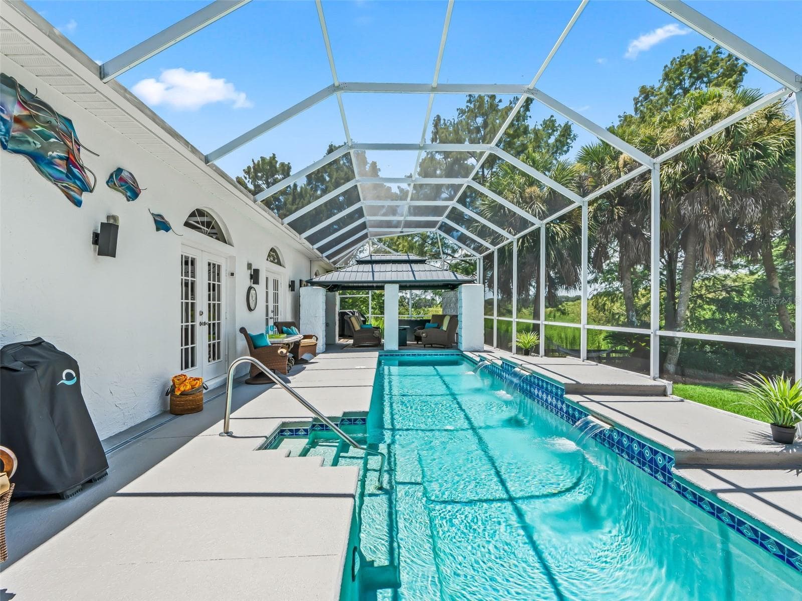 The long heated lap pool stretches across the screened enclosure, creating a true resort-style retreat with easy access to the home's multiple French doors. - 714 CIMARRON AVE, THE VILLAGES