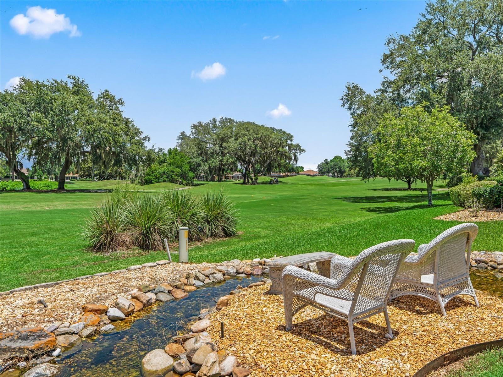 A charming seating area beside the water feature provides a quiet place to relax while taking in the long golf course views and lush surroundings. - 714 CIMARRON AVE, THE VILLAGES