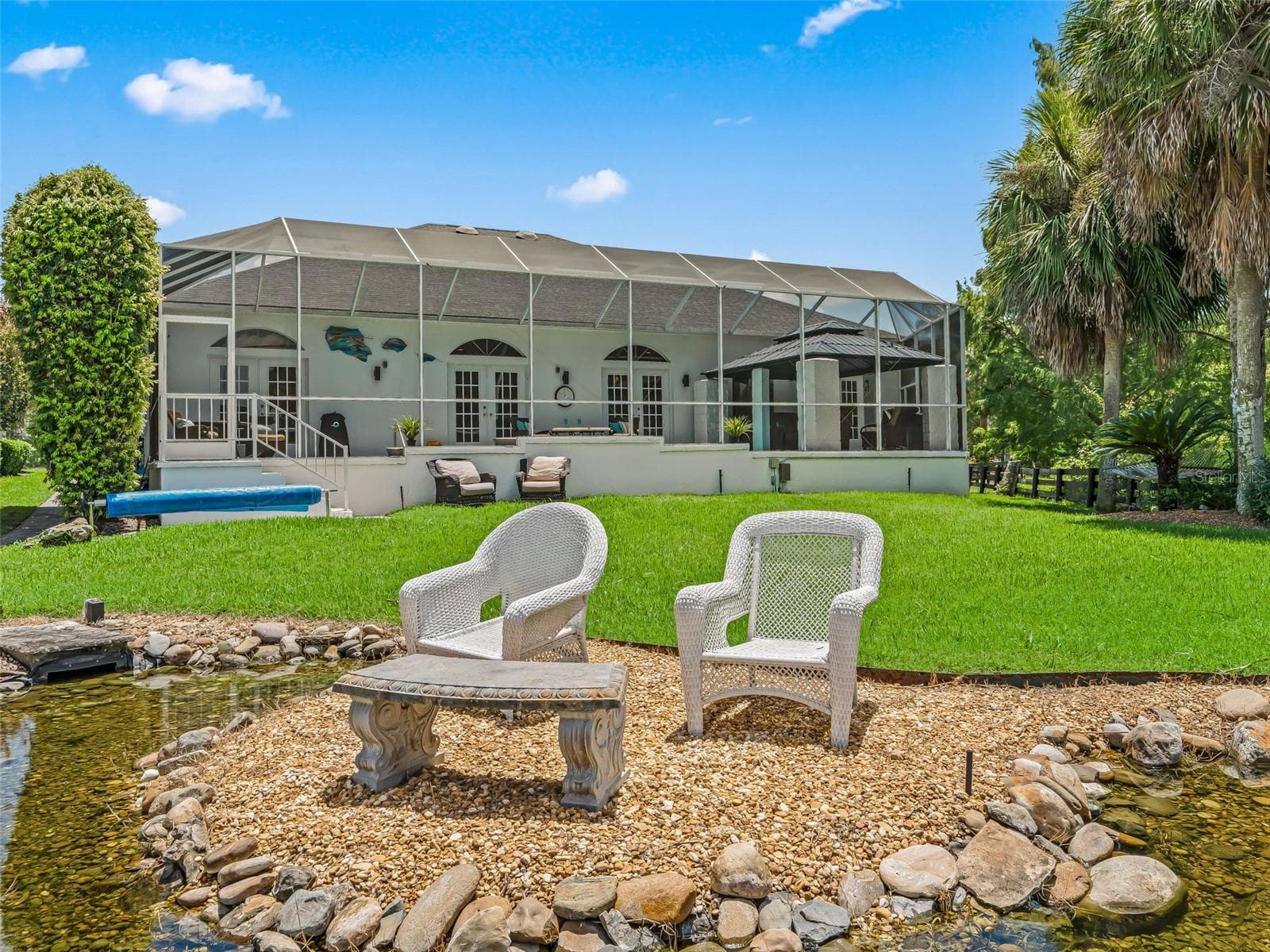 This view toward the home showcases the expansive screened pool enclosure, manicured lawn, and thoughtfully landscaped backyard retreat. - 714 CIMARRON AVE, THE VILLAGES
