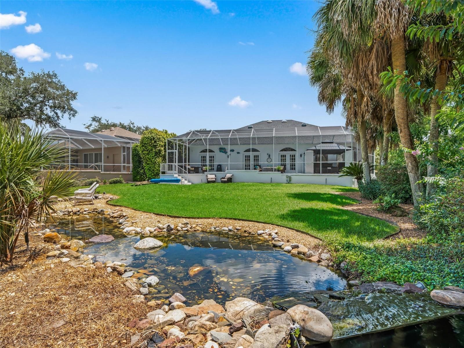 A picturesque backyard pond and waterfall create a tranquil focal point while enhancing the serene, resort-like atmosphere of this Premier property. - 714 CIMARRON AVE, THE VILLAGES
