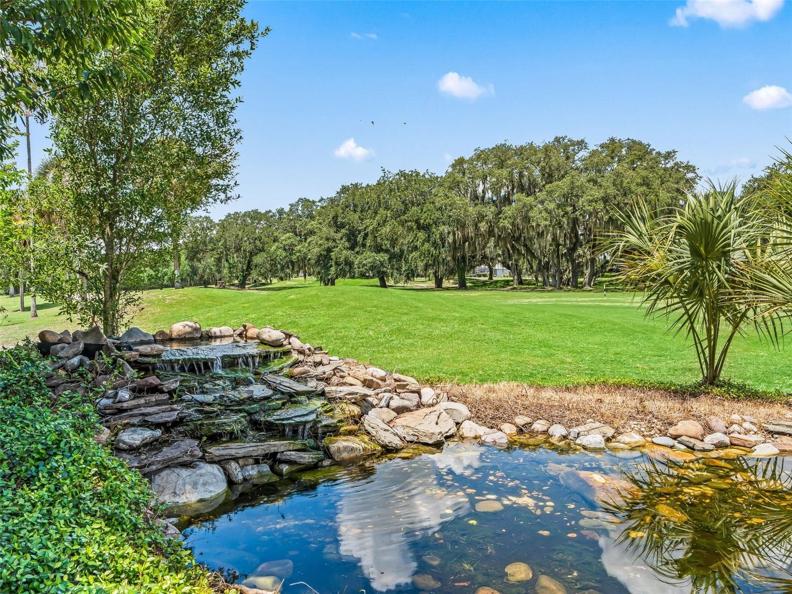 A closer view of the pond and rock waterfall showcases the thoughtful landscaping that adds beauty and peaceful ambiance to the outdoor setting. - 714 CIMARRON AVE, THE VILLAGES