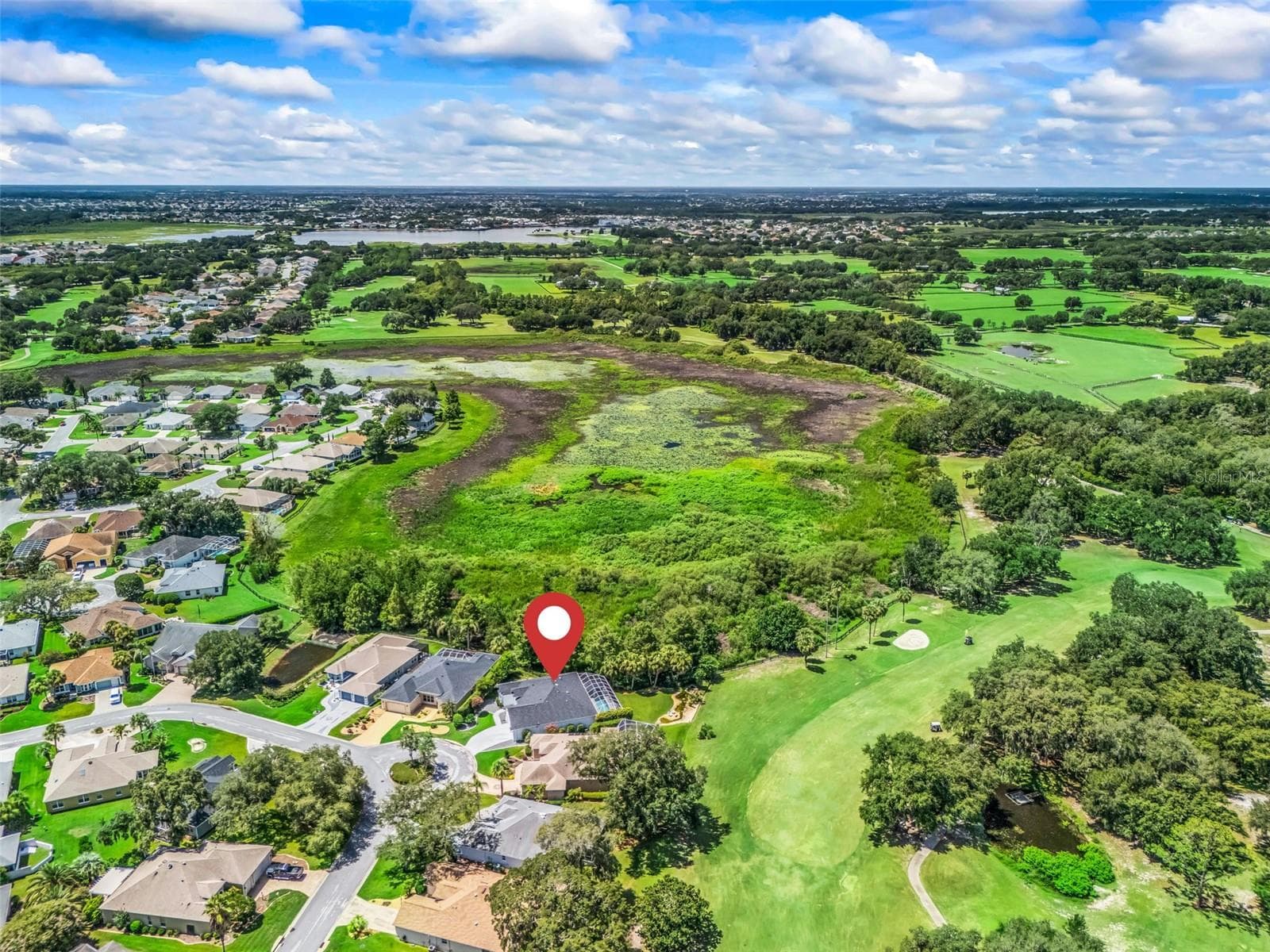 Dramatic aerial view captures the home's exceptional setting along the 10th fairway of Tierra Del Sol Championship Golf Course, with sweeping golf and preserve views that emphasize the privacy and natural beauty surrounding this one-of-a-kind property. - 714 CIMARRON AVE, THE VILLAGES