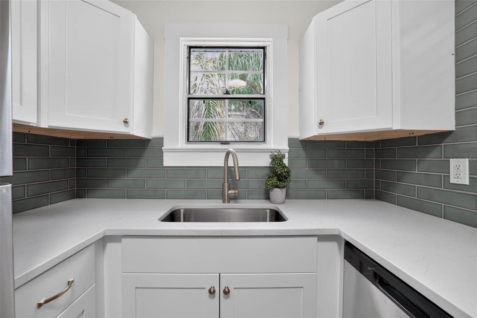 Bright kitchen sink area with quartz counters and soft green tile in this 1922 bungalow - 813 E NEW ORLEANS AVE, TAMPA