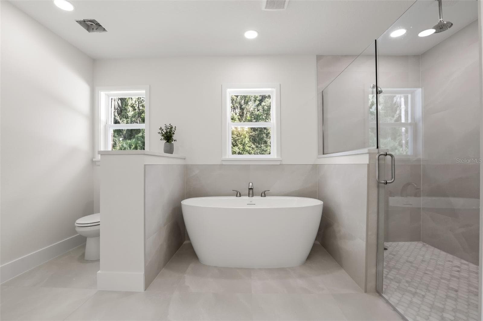 Enjoy a spa-like experience in the luxurious primary bathroom, complete with a freestanding soaking tub, oversized glass-enclosed shower, and serene natural light. - 39251 COUNTY ROAD 439, UMATILLA