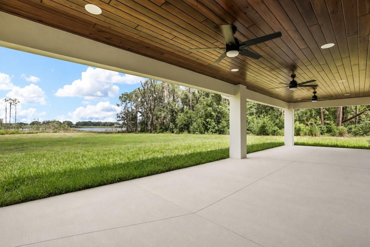 Spacious outdoor entertaining area with a stunning wood-plank ceiling, ceiling fans, and peaceful backyard views. - 39251 COUNTY ROAD 439, UMATILLA
