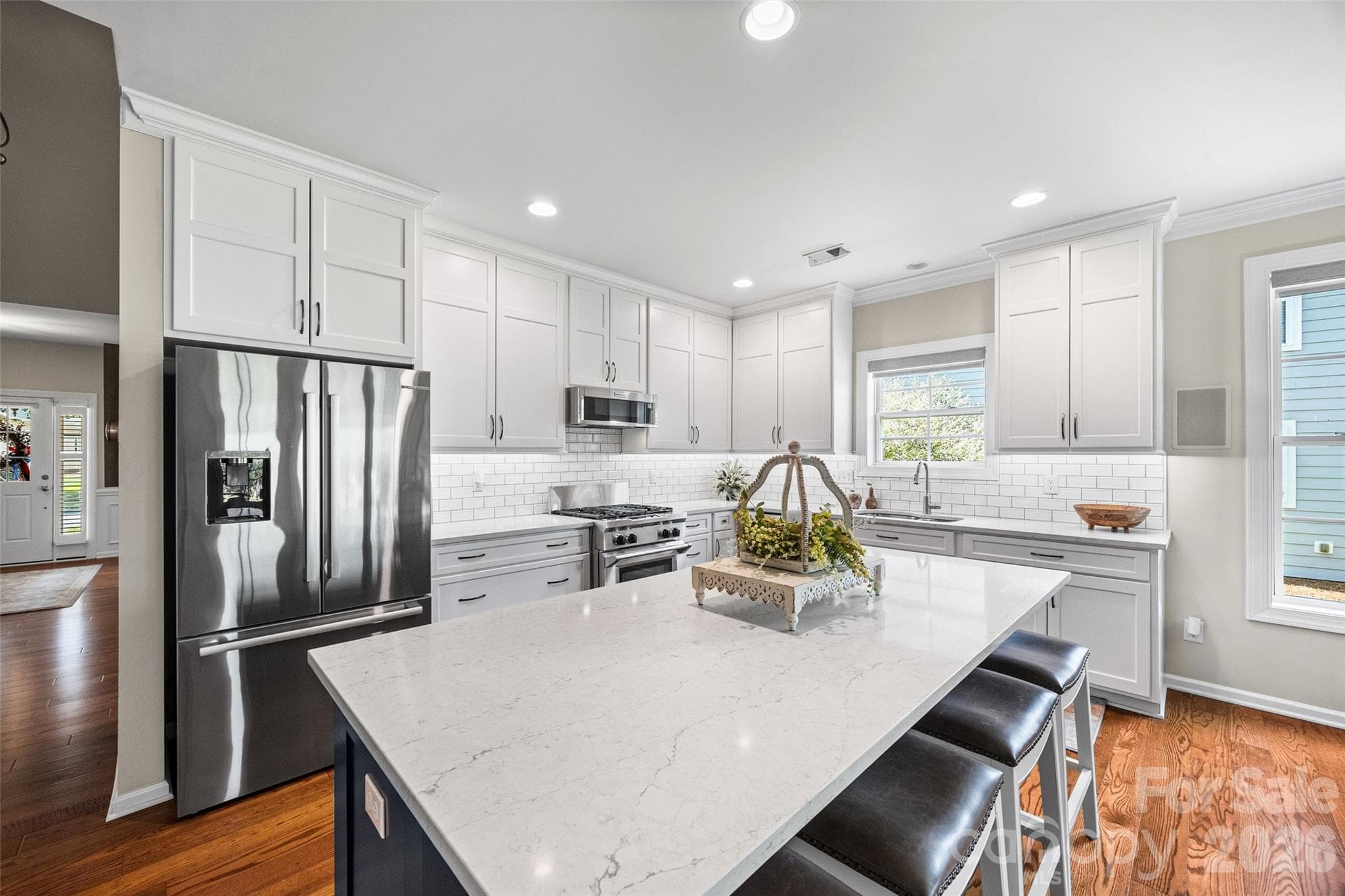 Gorgeous updated kitchen with tall cabinets, tiled backsplash and a generous kitchen island with barstool seating. - 8621 Sequoia Grove Lane, Charlotte