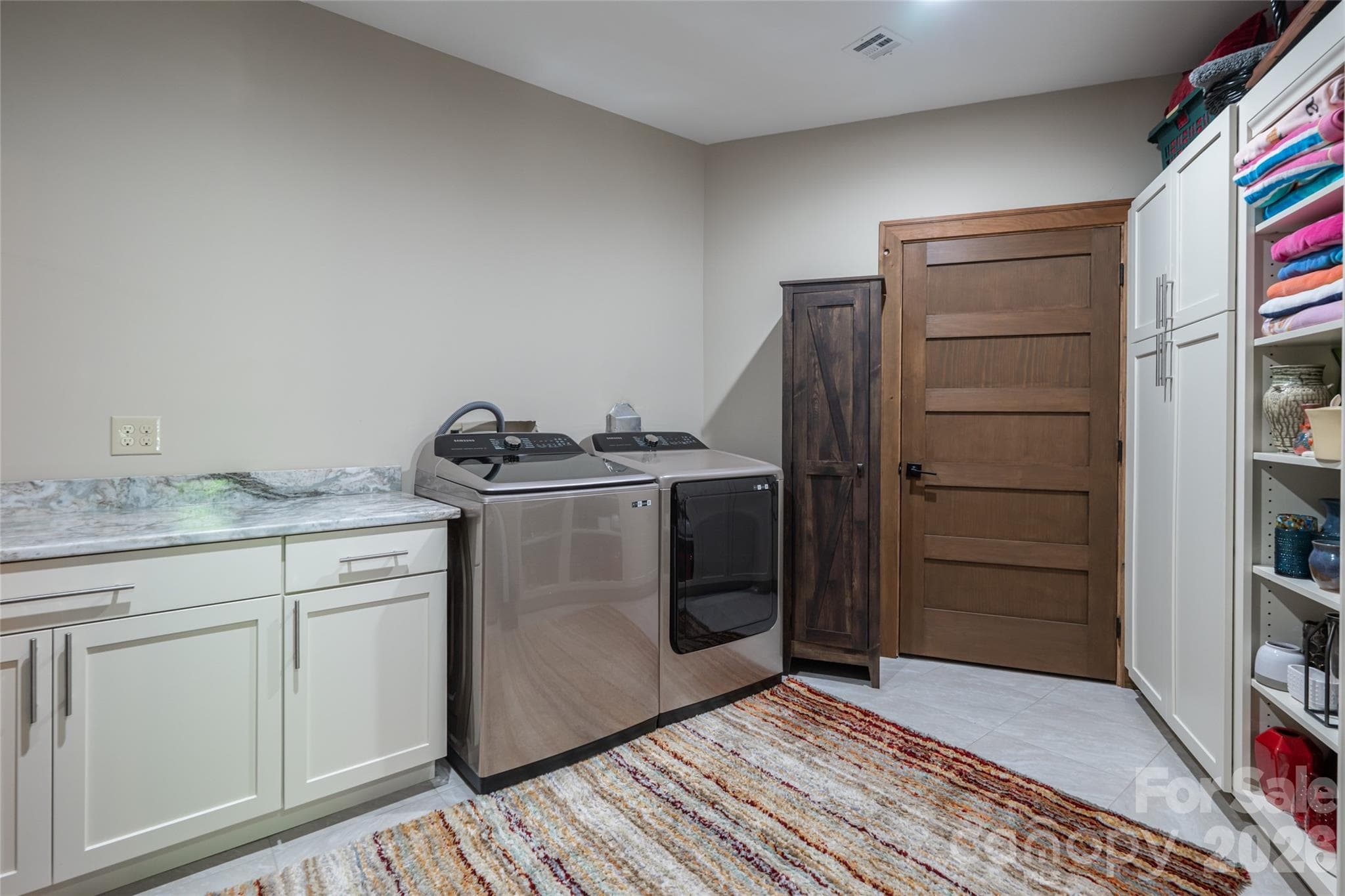 Oversized laundry room with storage closet, built-in shelving, and cabinetry. - 660 Pleasant Grove Road, Hendersonville