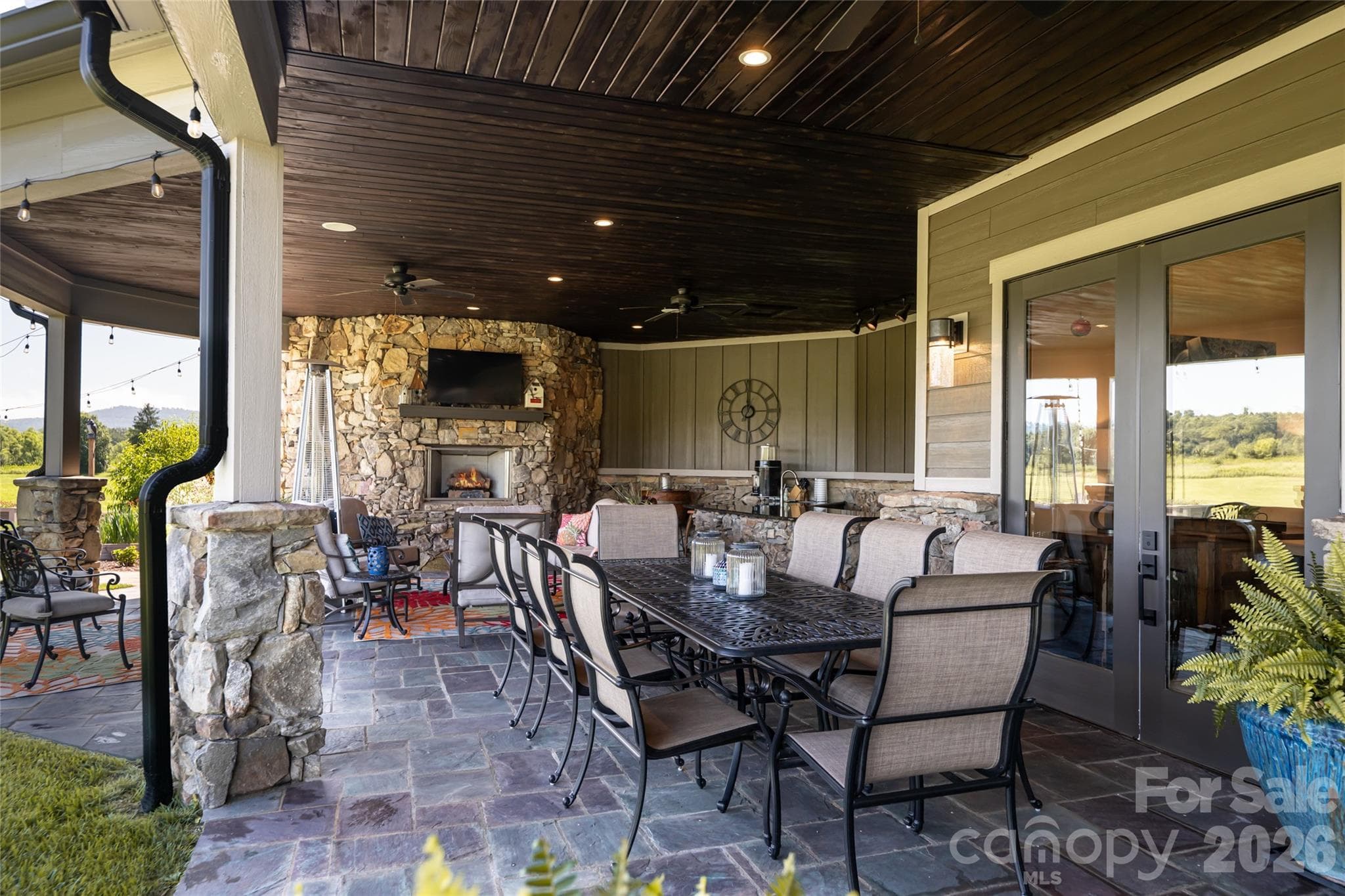 Covered outdoor patio boasts a large granite serving bar and TV seating area, creating the perfect space for entertaining and relaxation. - 660 Pleasant Grove Road, Hendersonville