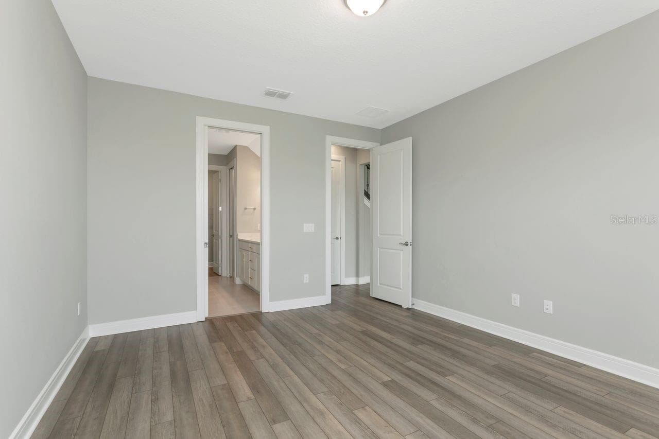 Primary Bedroom - 1st Floor, with backyard views,  luxury vinyl flooring with Ensuite Bath and Walk in Closet - 9909 LONGMEADOW AVE, PARRISH