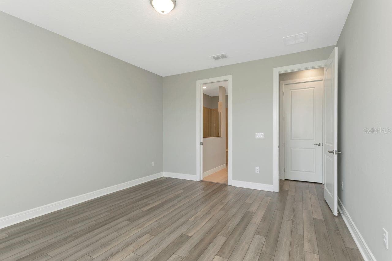Primary Bedroom - 1st Floor, with backyard views,  luxury vinyl flooring with Ensuite Bath and Walk in Closet - 9909 LONGMEADOW AVE, PARRISH