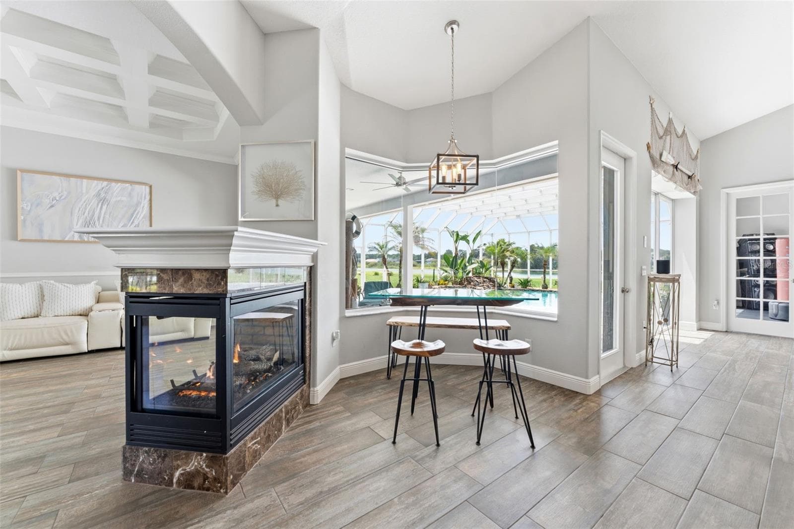 Captivating Views From the Breakfast Nook Featuring an Expansive, Aquarium-Style Glass Window and a Gas Operating Fireplace - 24355 HIDEOUT TRL, LAND O LAKES