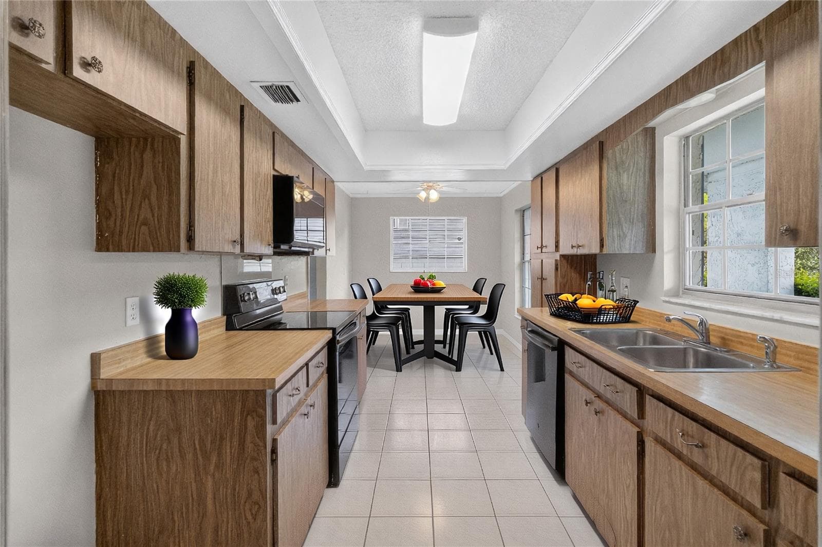 Kitchen is light and bright - having three (3) windows with a window over the kitchen sink. A front-facing kitchen sink window brings in natural light and lets us keep an eye on what’s happening in the front of our home — deliveries, guests arriving, kids playing. (Virtual stage table / accessories) - 656 LITTLE WEKIVA RD, ALTAMONTE SPRINGS