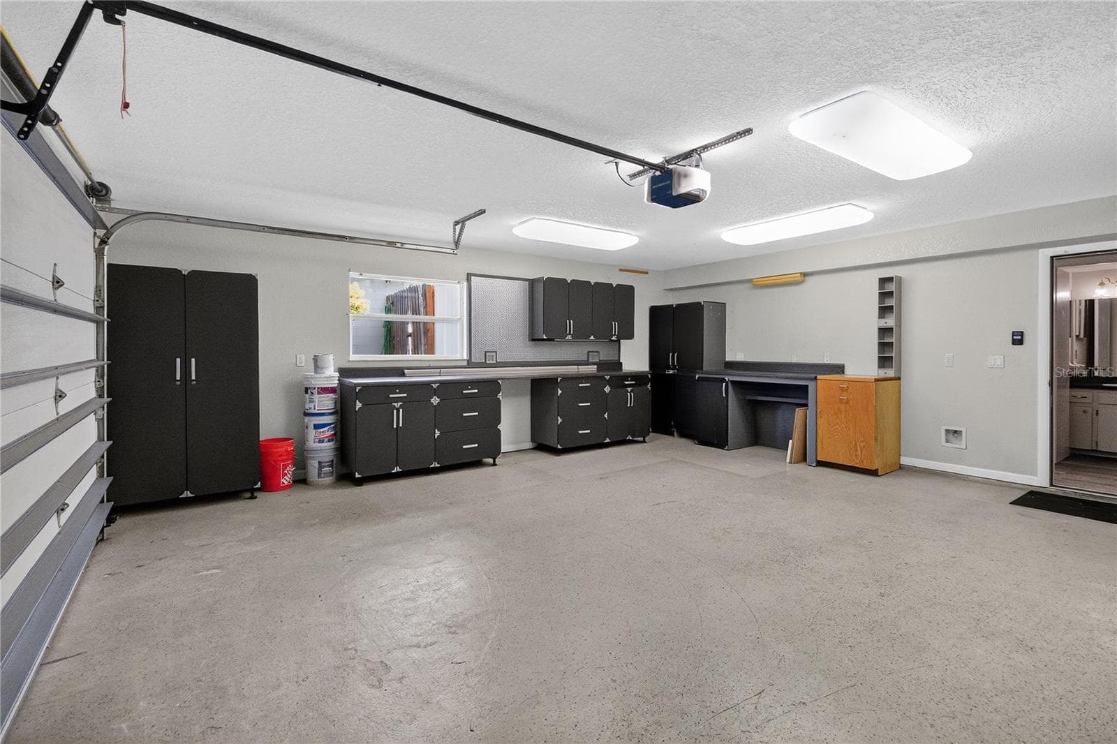 View 3 - Garage w/ cabinetry, shelving strategically placed electrical outlets throughout w/ WORKSHOP lighting. - showing EASE of access to hallway for 1/2 bath. - 656 LITTLE WEKIVA RD, ALTAMONTE SPRINGS