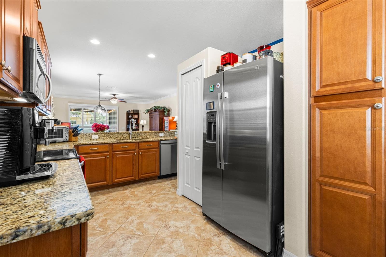 The kitchen includes a pantry and stainless appliances, including a 2026 GE refrigerator and 2025 LG dishwasher, with the range and microwave completing the suite. - 9524 TRUMPET VINE LOOP, NEW PORT RICHEY