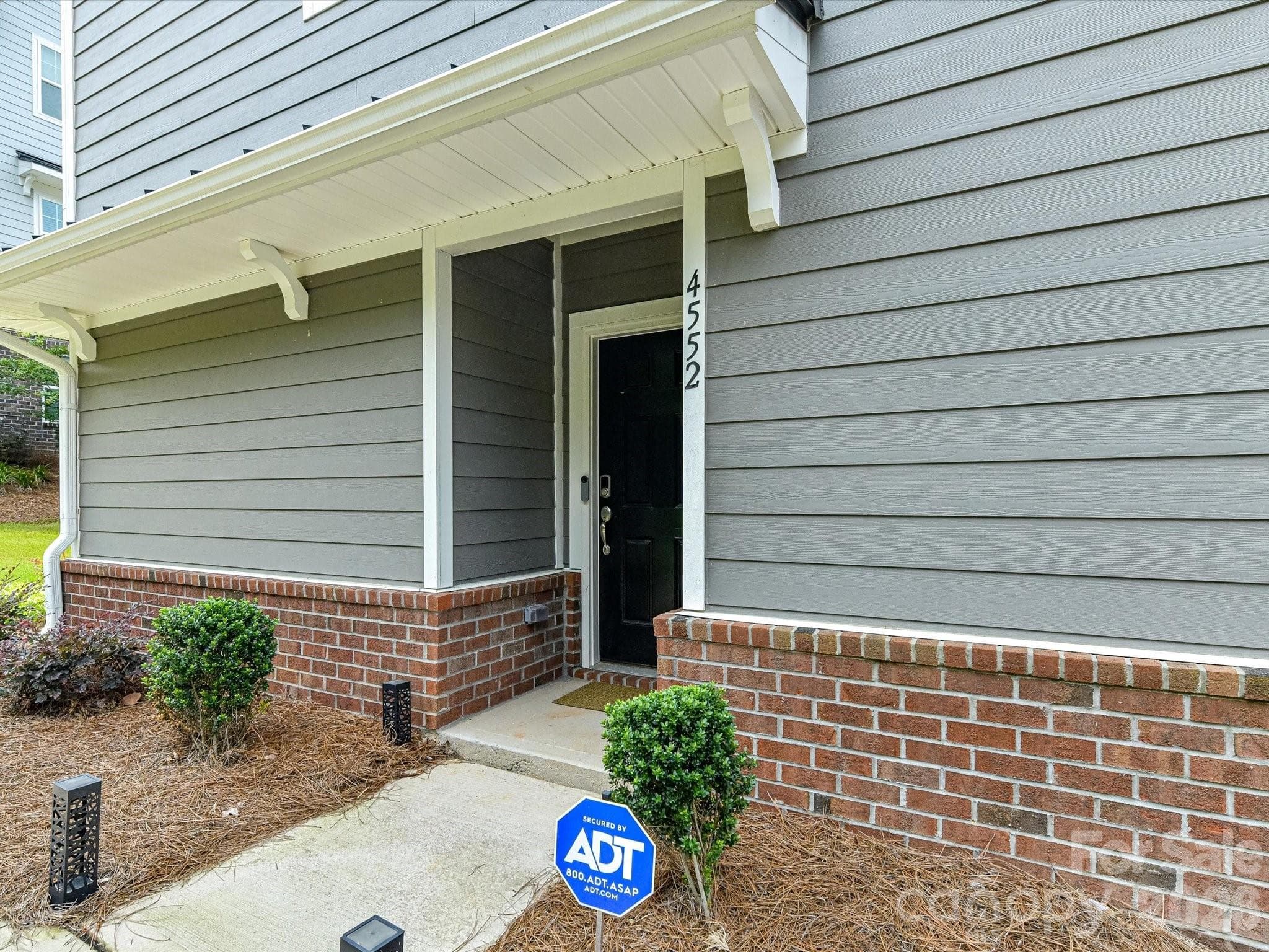 Beautifully maintained three-story home with modern curb appeal, professional landscaping, and a welcoming covered entry. - 4552 Millennium Avenue, Charlotte