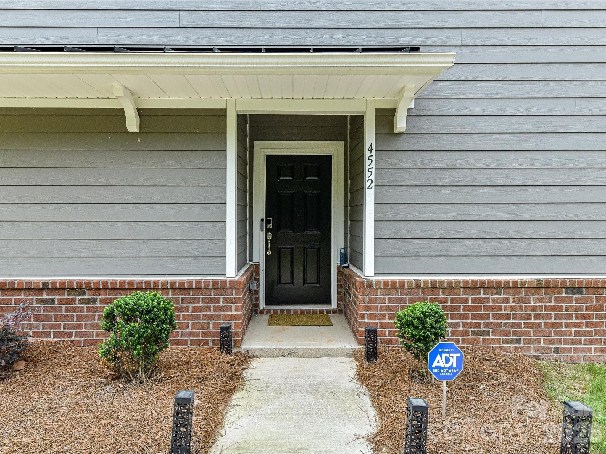 Beautifully maintained three-story home with modern curb appeal, professional landscaping, and a welcoming covered entry. - 4552 Millennium Avenue, Charlotte