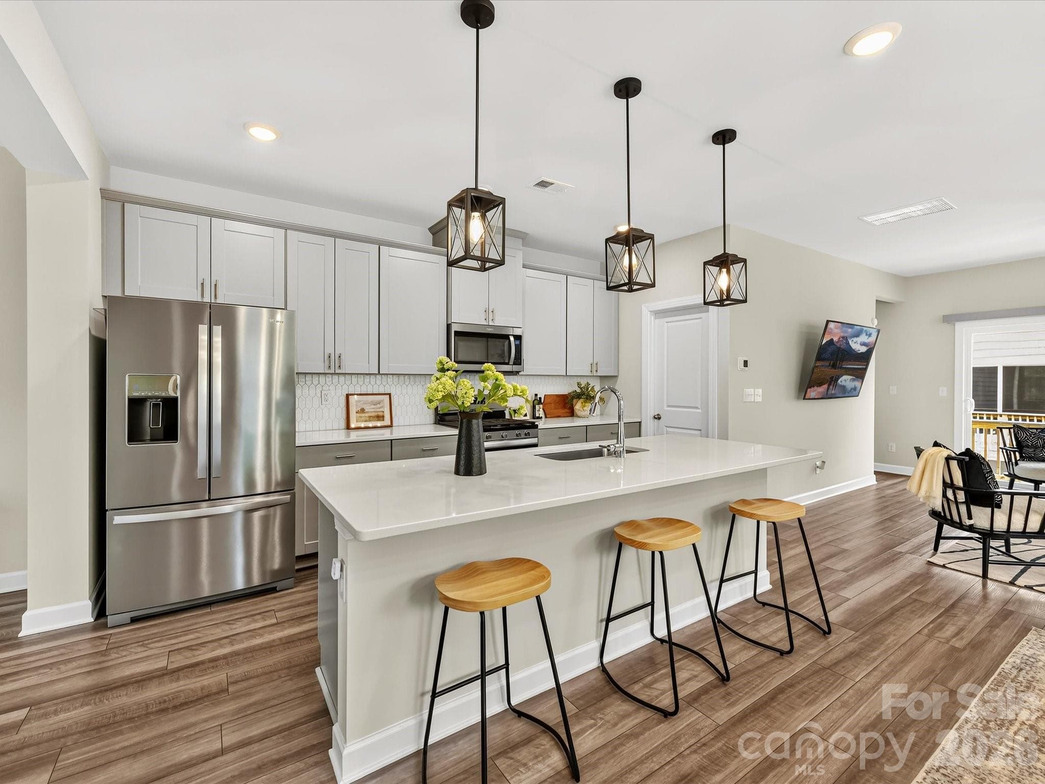 The chef-inspired kitchen showcases a large island, abundant cabinetry, stainless steel appliances, and designer lighting. - 4552 Millennium Avenue, Charlotte