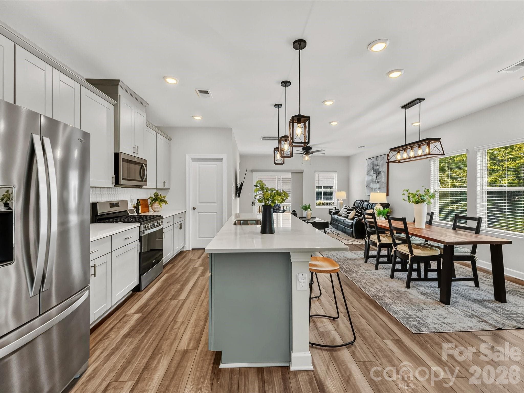 The chef-inspired kitchen showcases a large island, abundant cabinetry, stainless steel appliances, and designer lighting. - 4552 Millennium Avenue, Charlotte