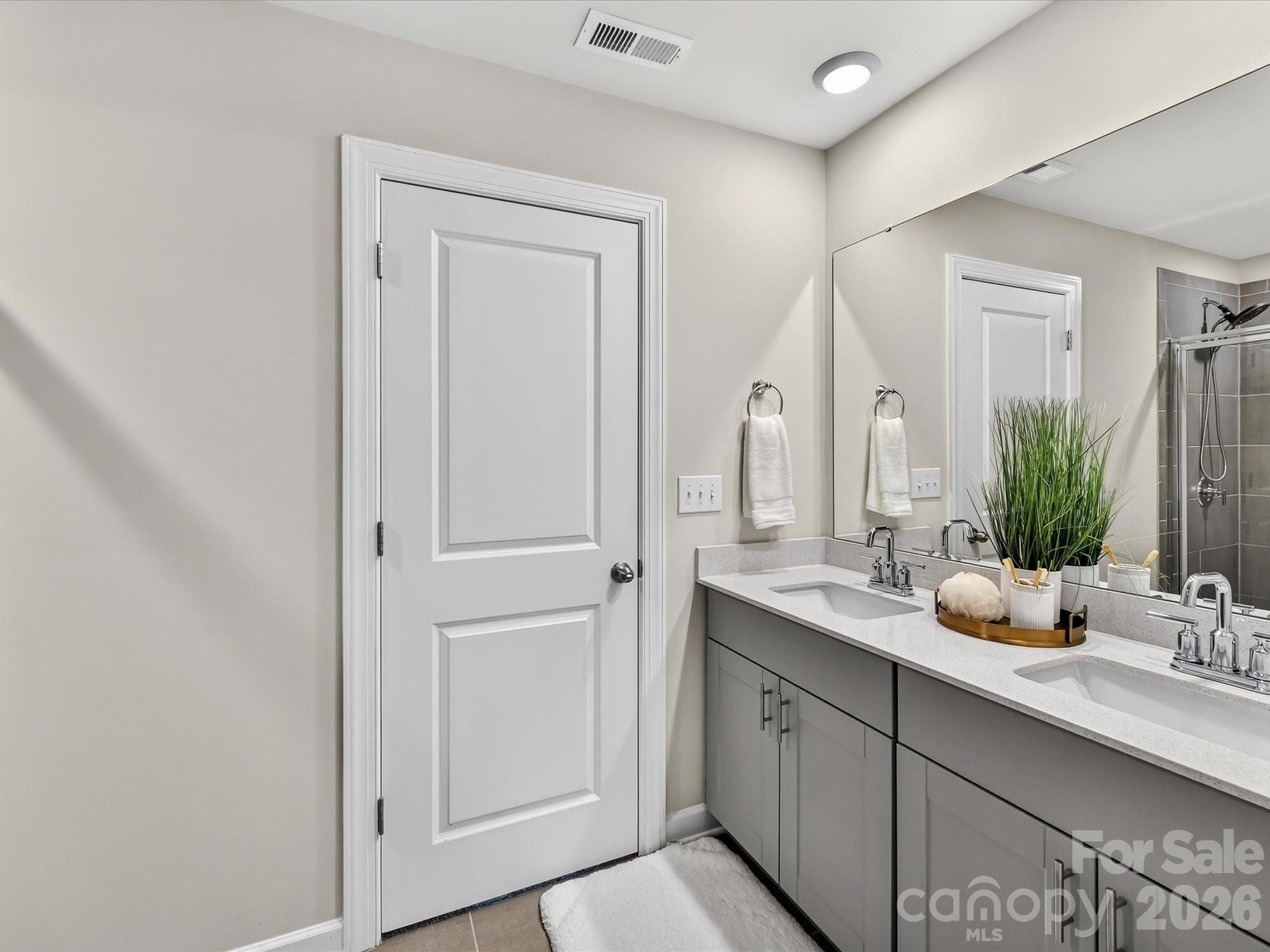 Spa-inspired primary bathroom features dual vanities, a spacious walk-in shower, and ample storage. - 4552 Millennium Avenue, Charlotte