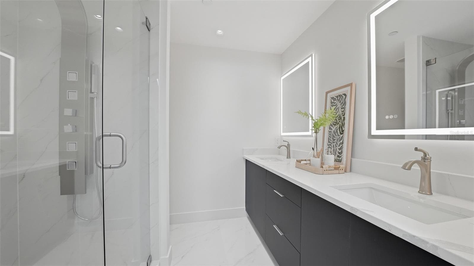 Primary Suite bathroom features bright all white finishes with contrasting custom cabinetry with dual sinks, LED mirrors, walk in shower with Euro glass shower system. - 430 KUMQUAT CT #202, SARASOTA