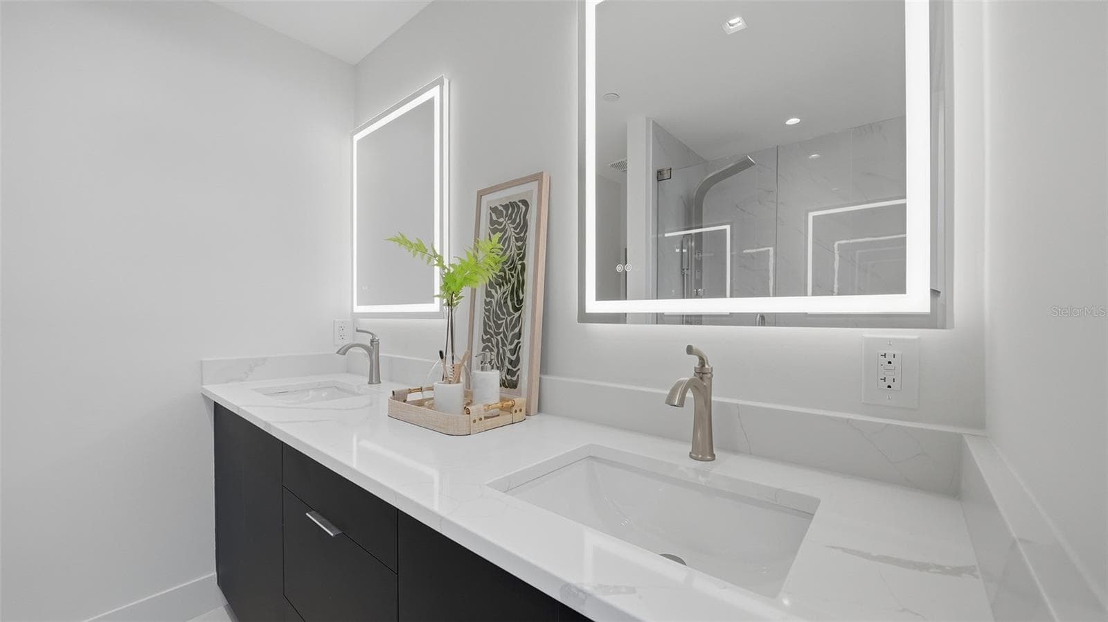 Primary Suite bathroom features bright all white finishes with contrasting custom cabinetry with dual sinks, LED mirrors, walk in shower with Euro glass shower system. - 430 KUMQUAT CT #202, SARASOTA
