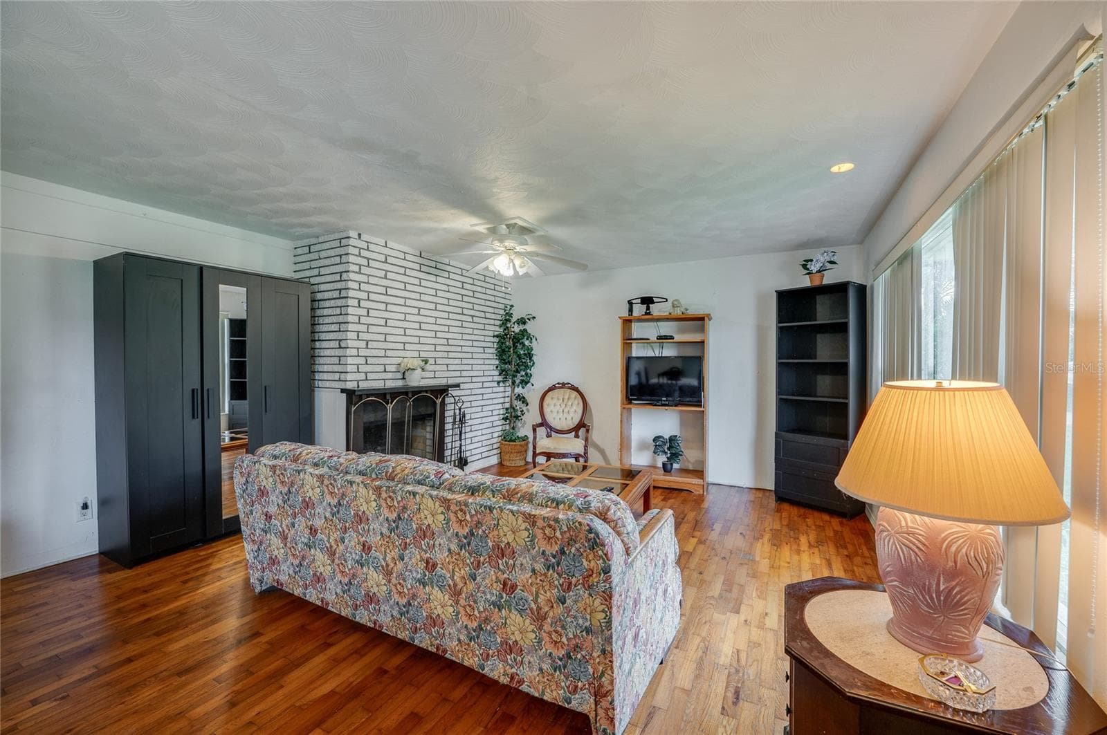 Warm living area featuring rich hardwood flooring, and a painted brick fireplace. Large windows bring in ample natural light to illuminate the inviting space. - 1101 16TH ST, EDGEWATER