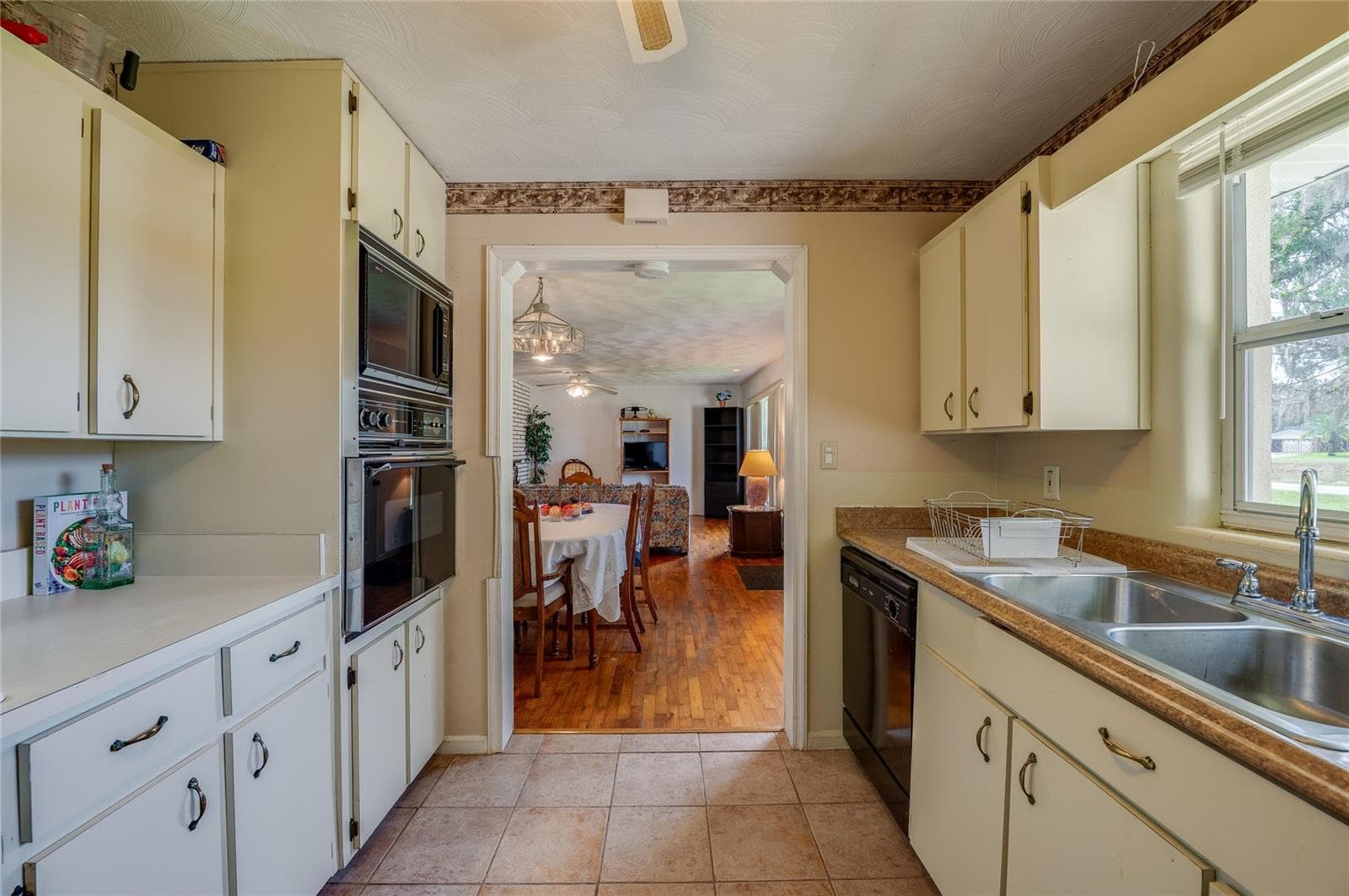 Centrally located kitchen framed by wall oven and ample cabinet storage, looking through an open doorway into the main living space. - 1101 16TH ST, EDGEWATER