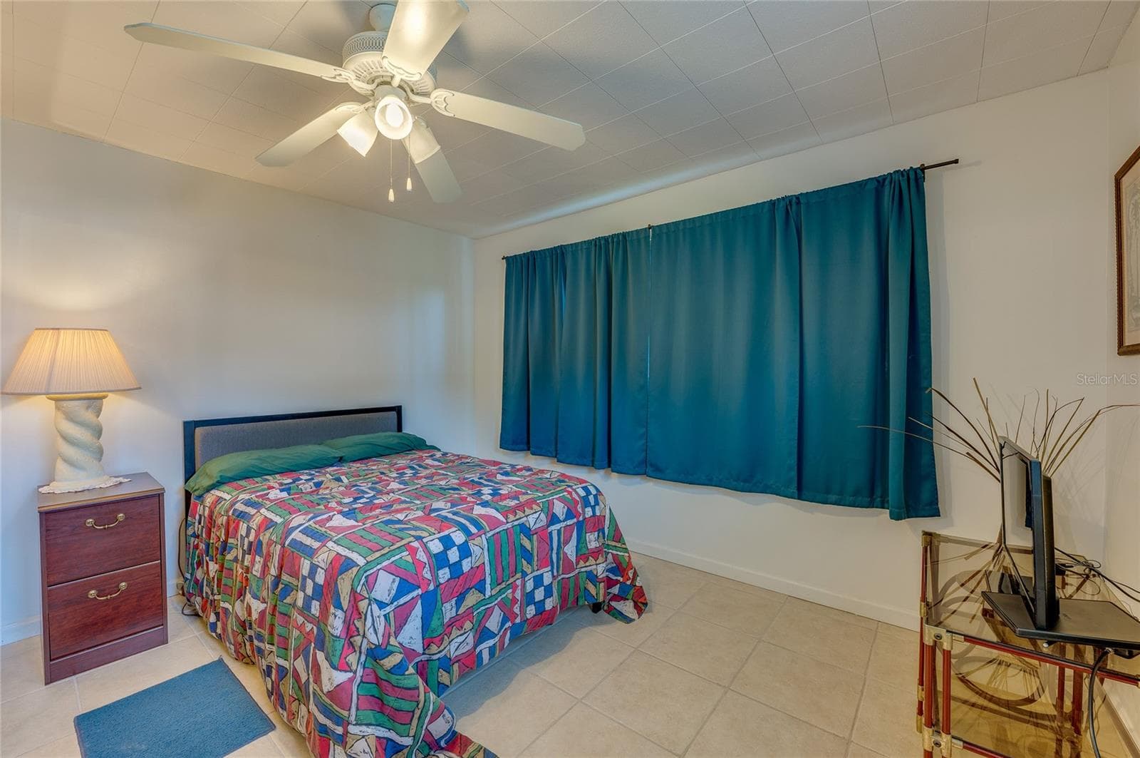 In-Law suite with it’s own outside entrance featuring neutral tile flooring, an overhead ceiling fan, and a large window accented by full-length teal drapes. - 1101 16TH ST, EDGEWATER