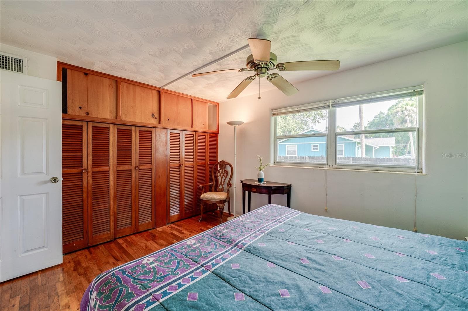 Light-filled bedroom featuring built-in closet storage, rich wood floors, and an overhead ceiling fan. Wide windows deliver pleasant outdoor views and plenty of daytime illumination. - 1101 16TH ST, EDGEWATER