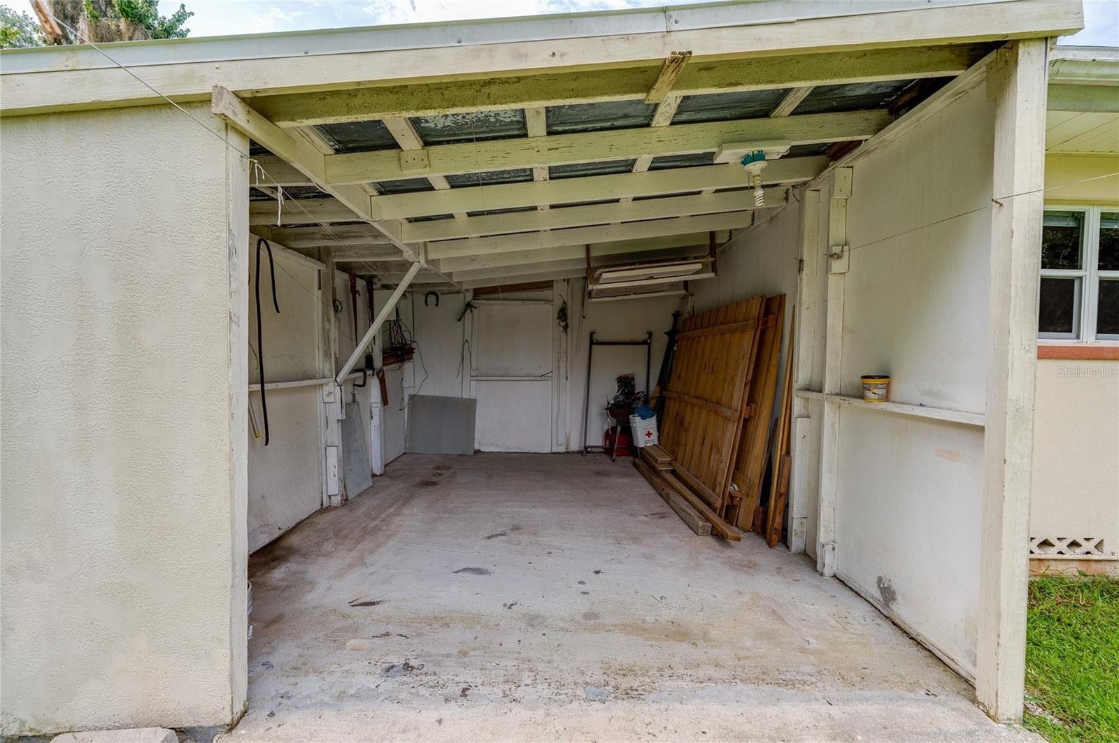 Carport featuring a concrete floor, high wooden rafters, and an attached side wall for additional shelter. - 1101 16TH ST, EDGEWATER