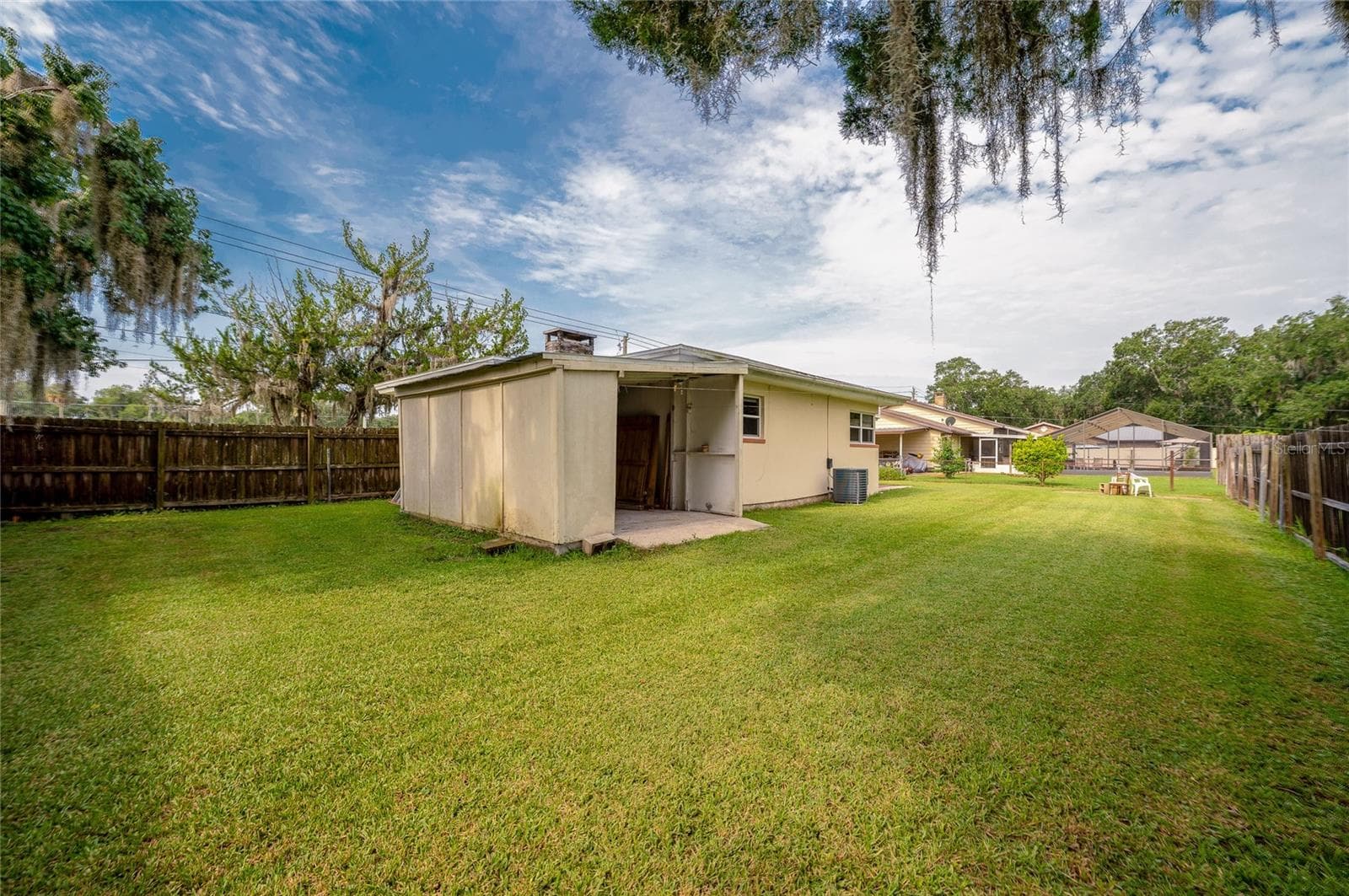 Large green yard featuring a fully fenced perimeter, mature oak trees with Spanish moss, and an attached garage. - 1101 16TH ST, EDGEWATER