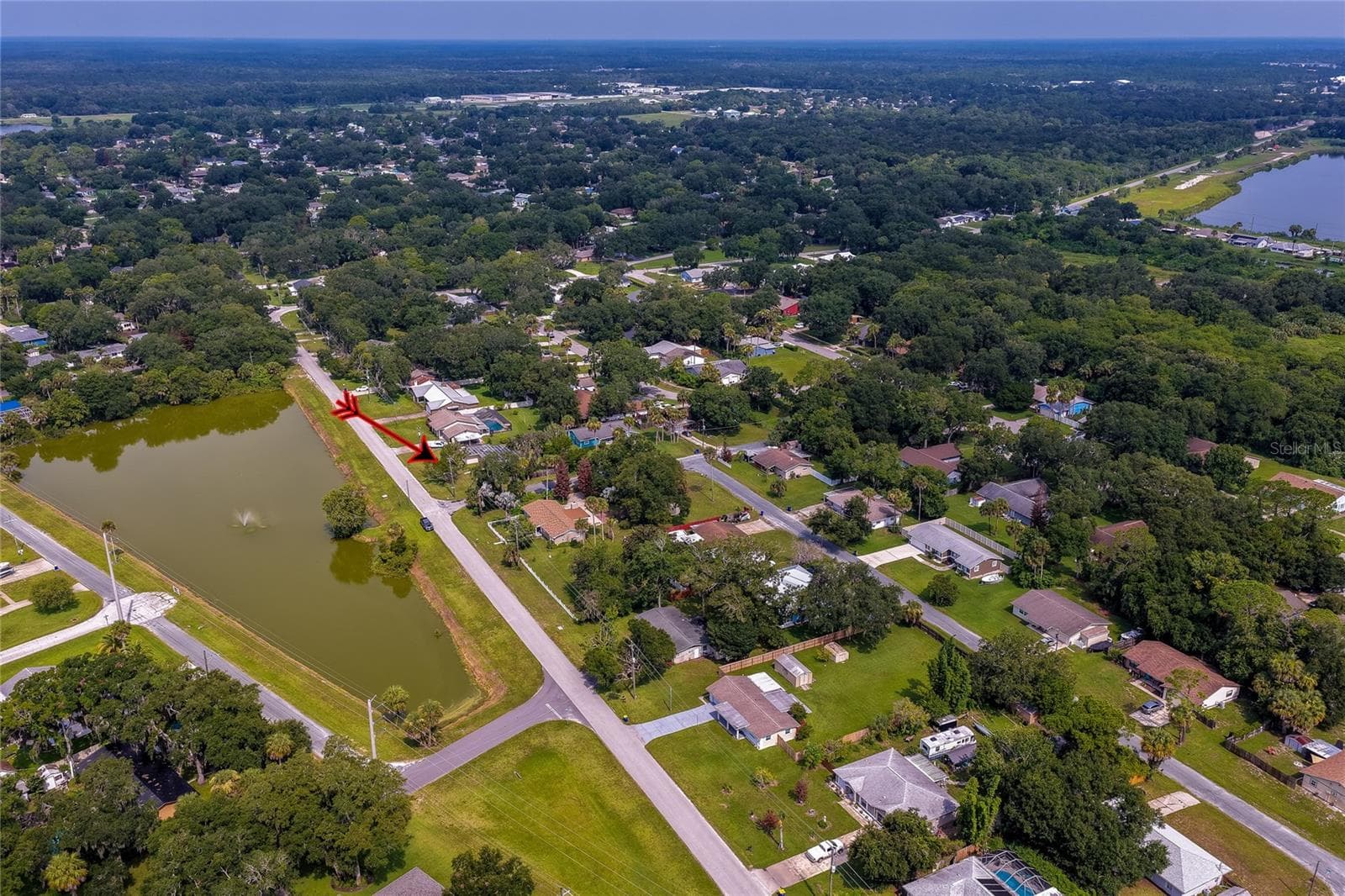 Wide-angle aerial perspective showing the home nestled in a quiet, tree-lined neighborhood adjacent to a large body of water. - 1101 16TH ST, EDGEWATER